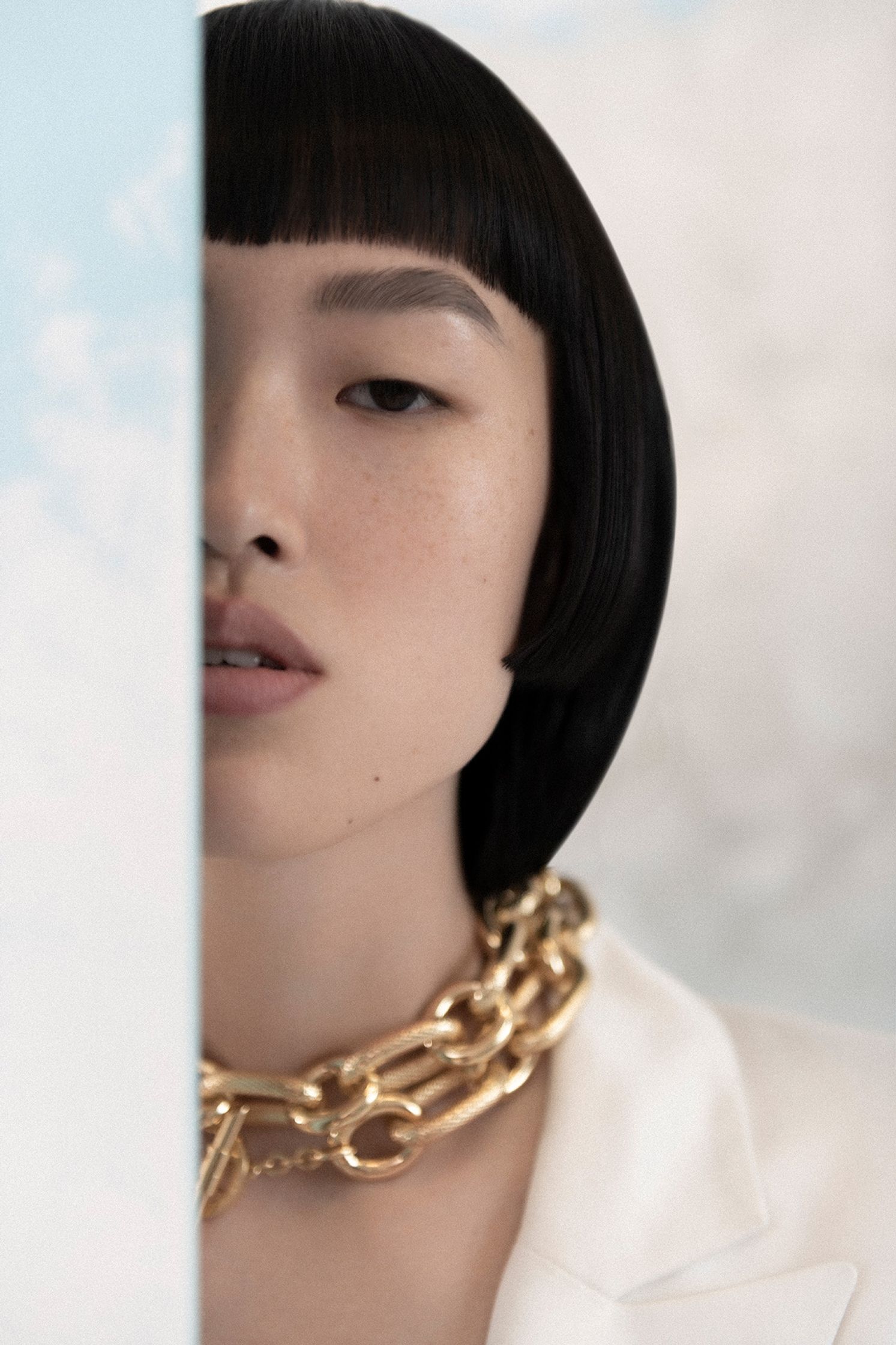 a woman in a white shirt with a gold chain necklace