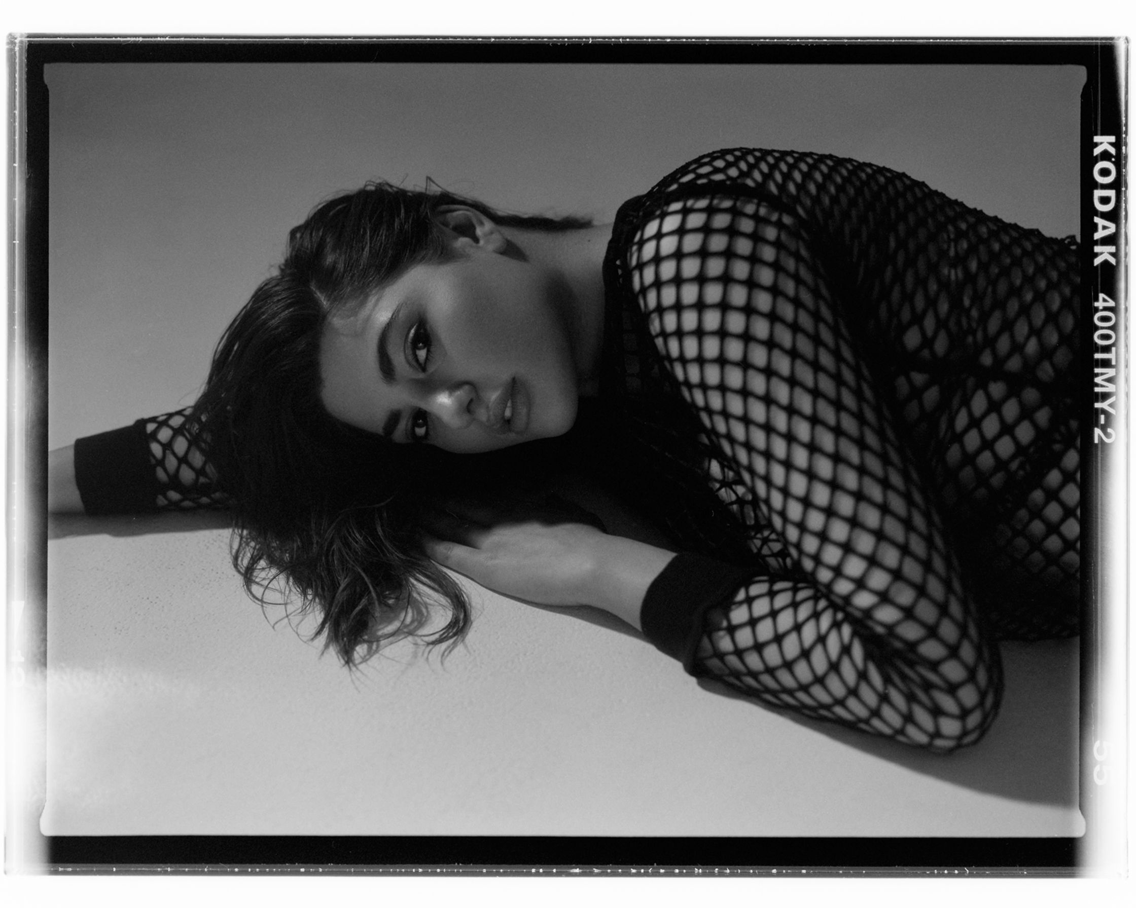 a black and white photo of a woman in a fishnet top