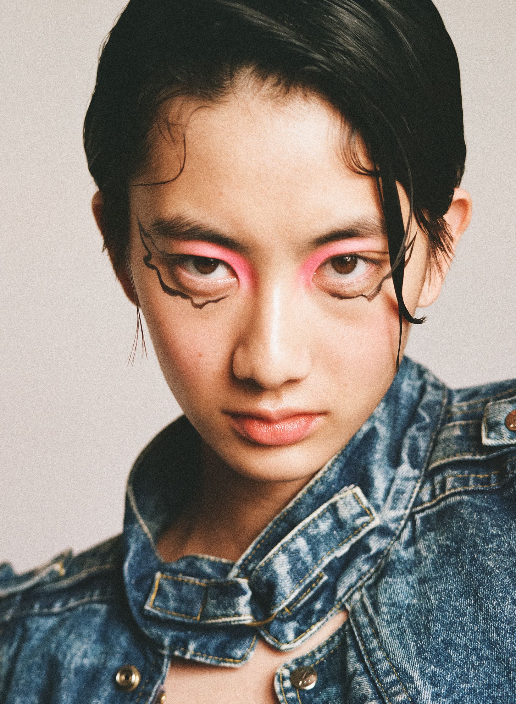 a girl with pink eye makeup and a denim jacket