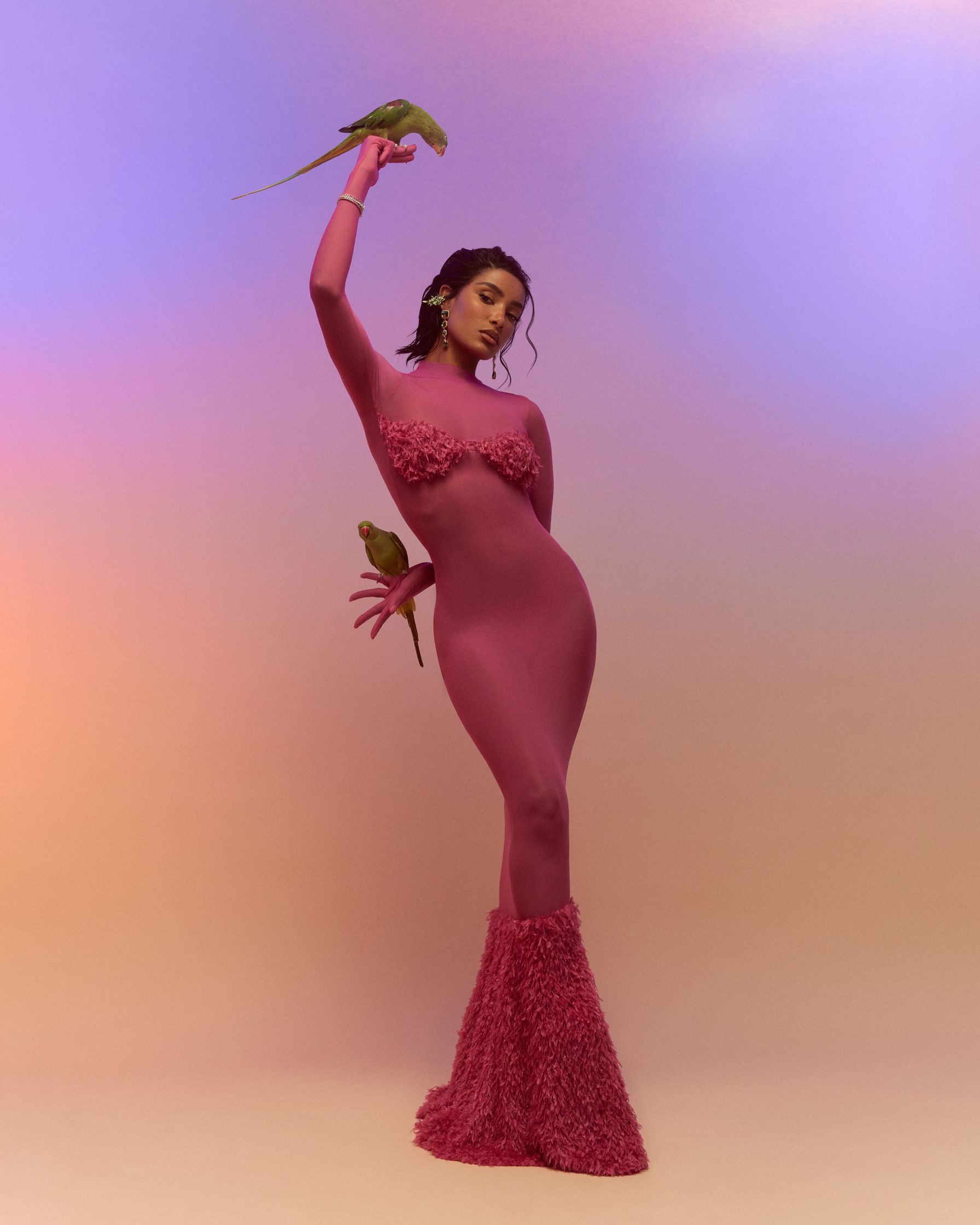 a woman in a pink dress holding a parrot