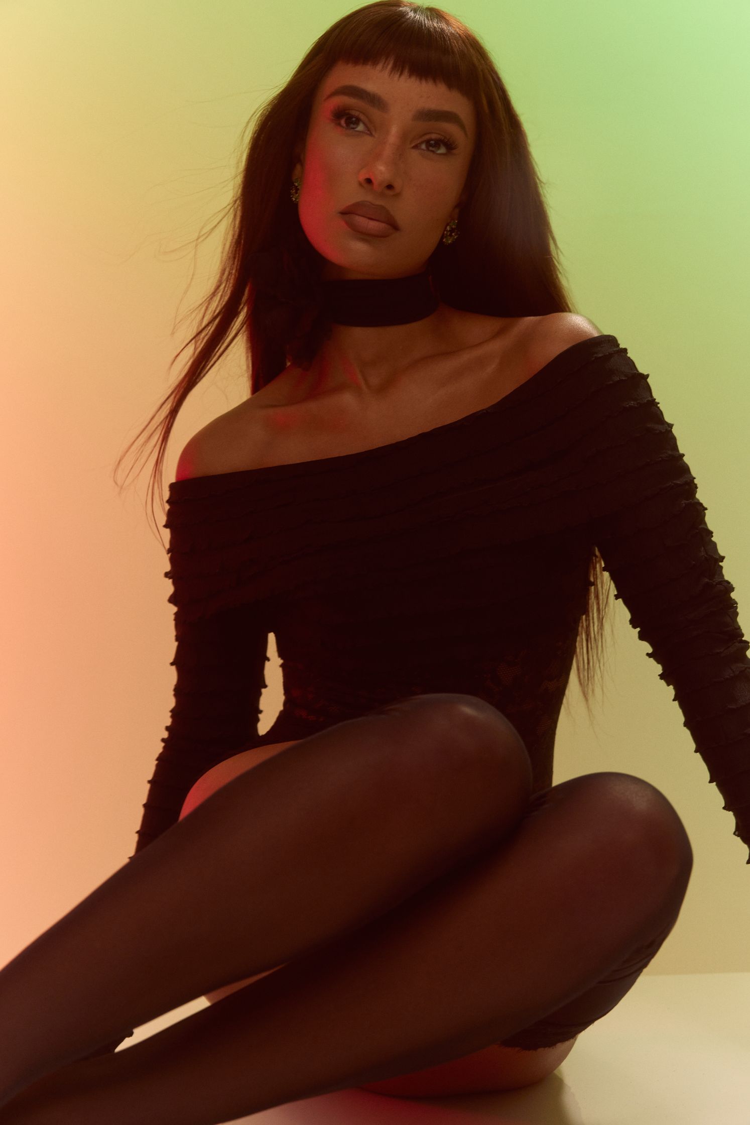 a woman in black stockings posing in front of a colorful background