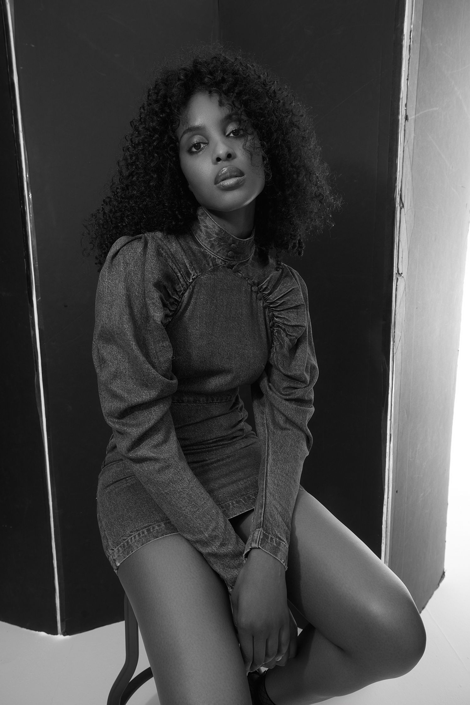 a black and white photo of a woman sitting on a stool