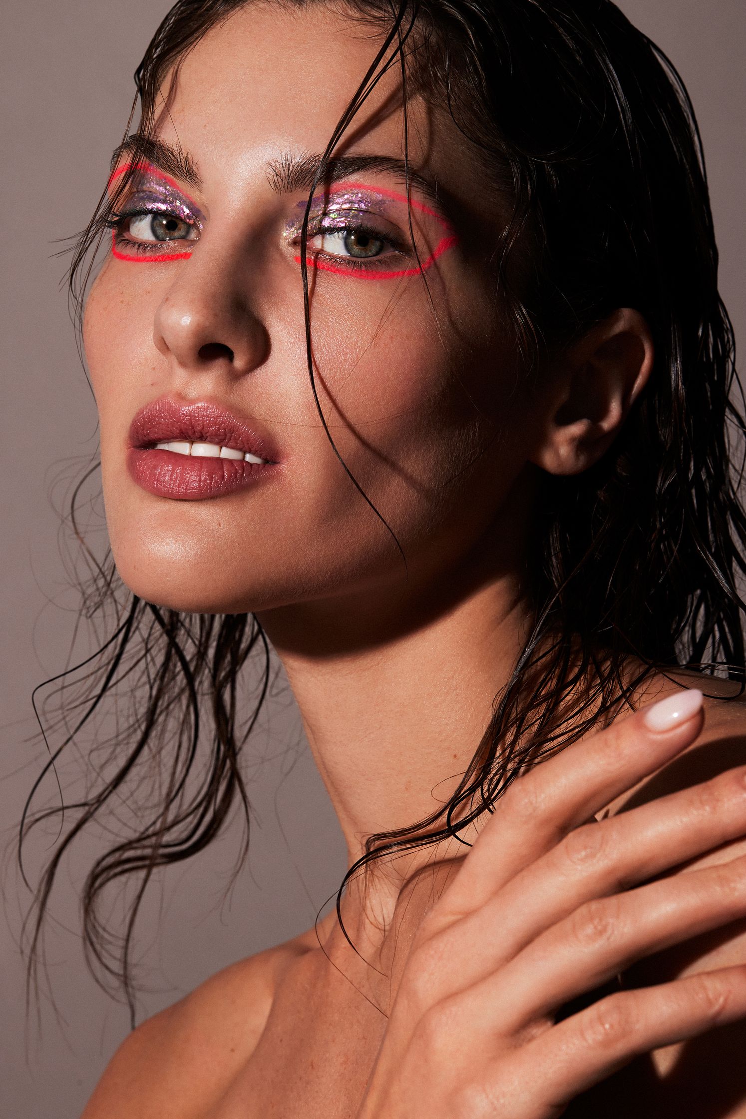a woman with pink eye makeup posing with her hands in the water