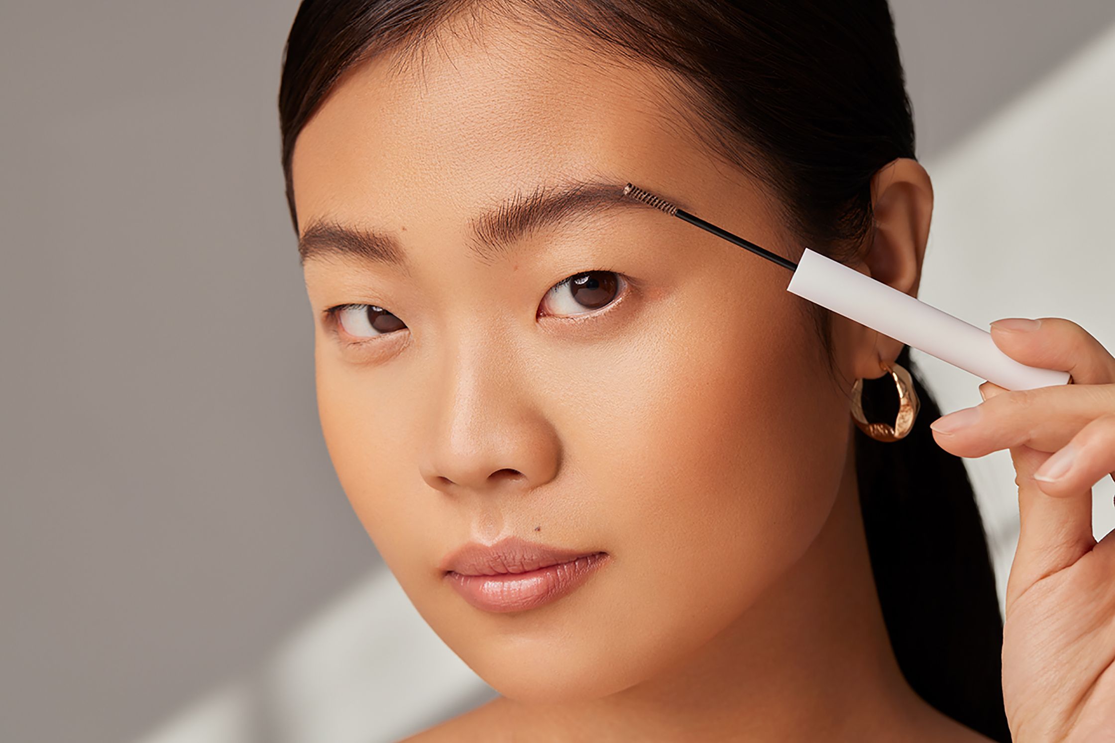 a woman is using a pencil to draw her eyebrows