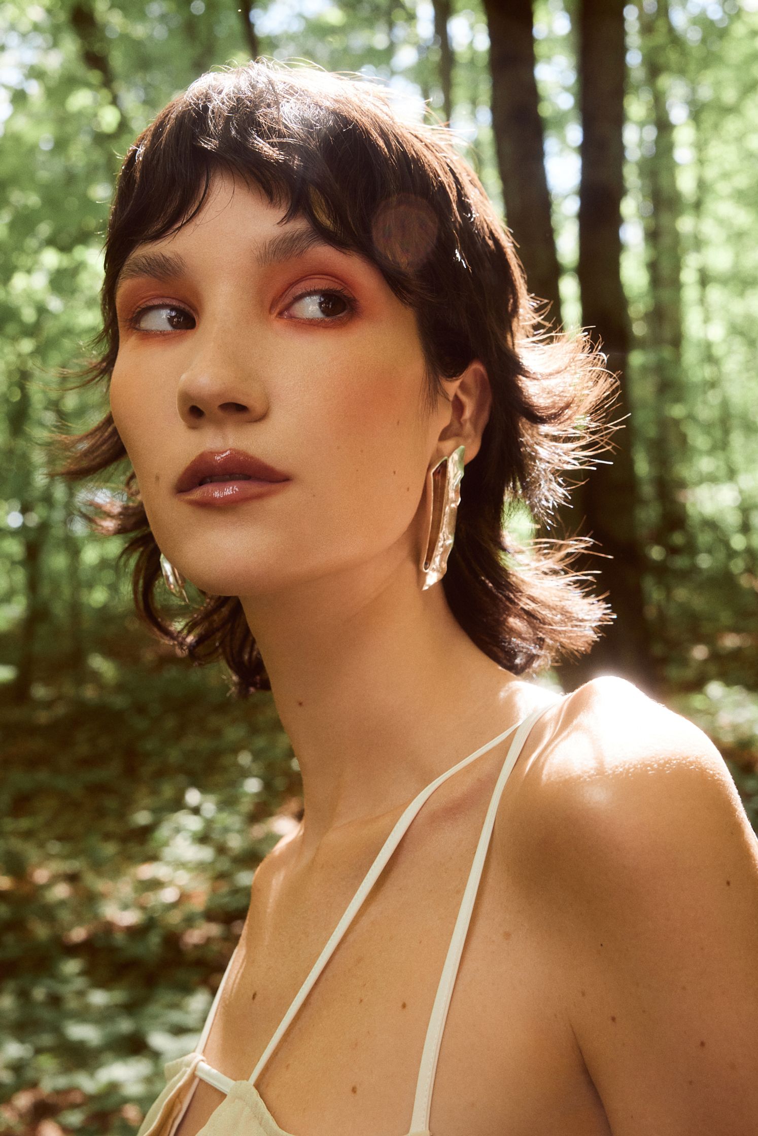 a woman in a white dress is standing in the woods