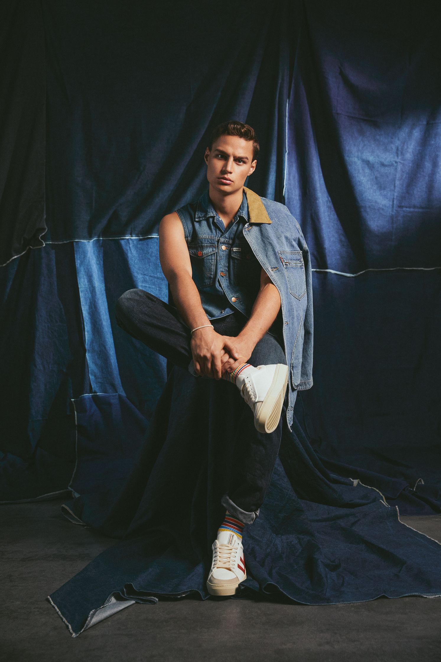 a man in a denim jacket sitting on top of a blue cloth