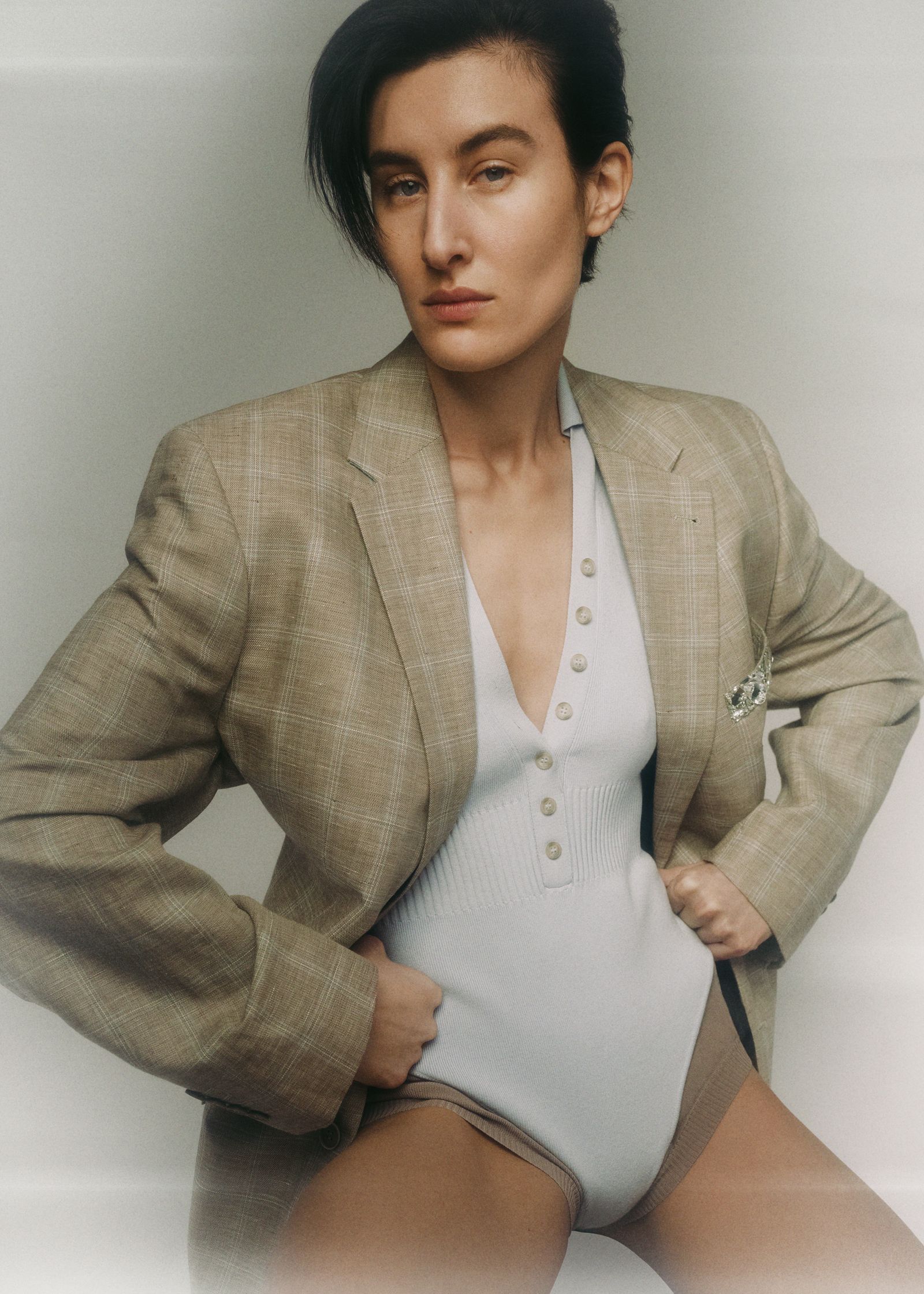 a woman is posing in a blazer and underwear