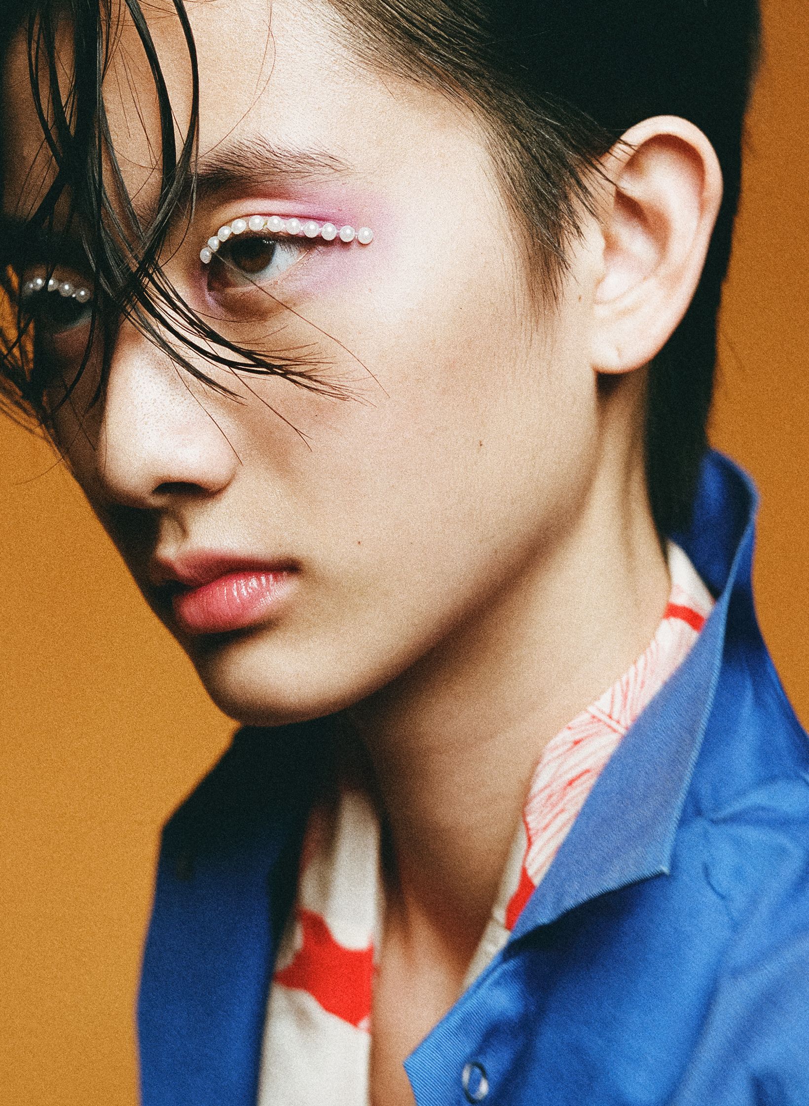 a young asian woman wearing a blue shirt and pink eye makeup