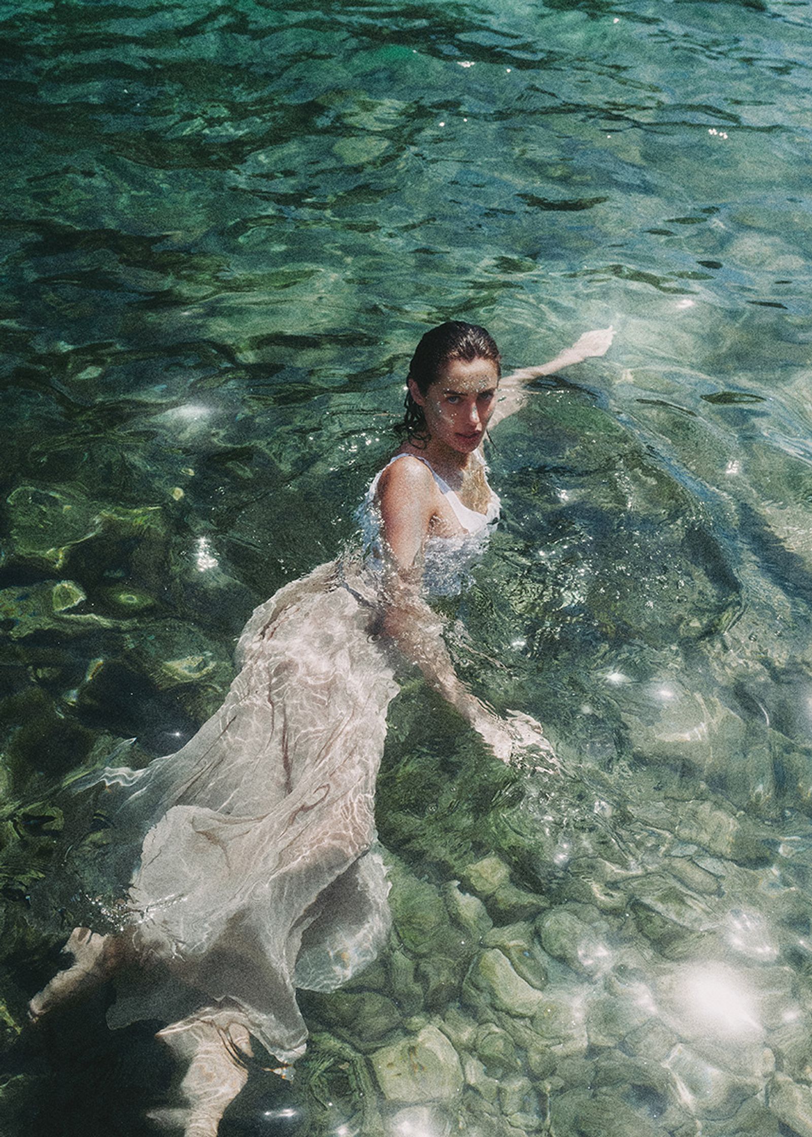 a woman in a white dress floating in clear water
