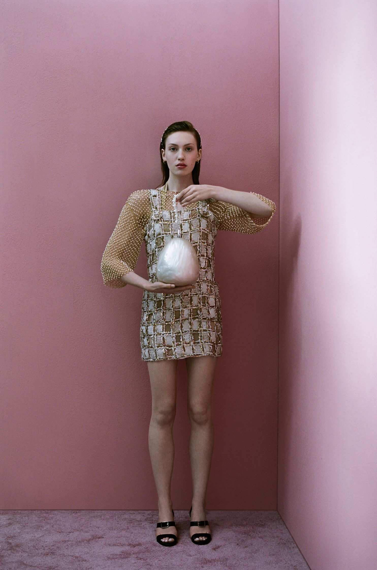a woman in a white dress standing in front of a pink wall