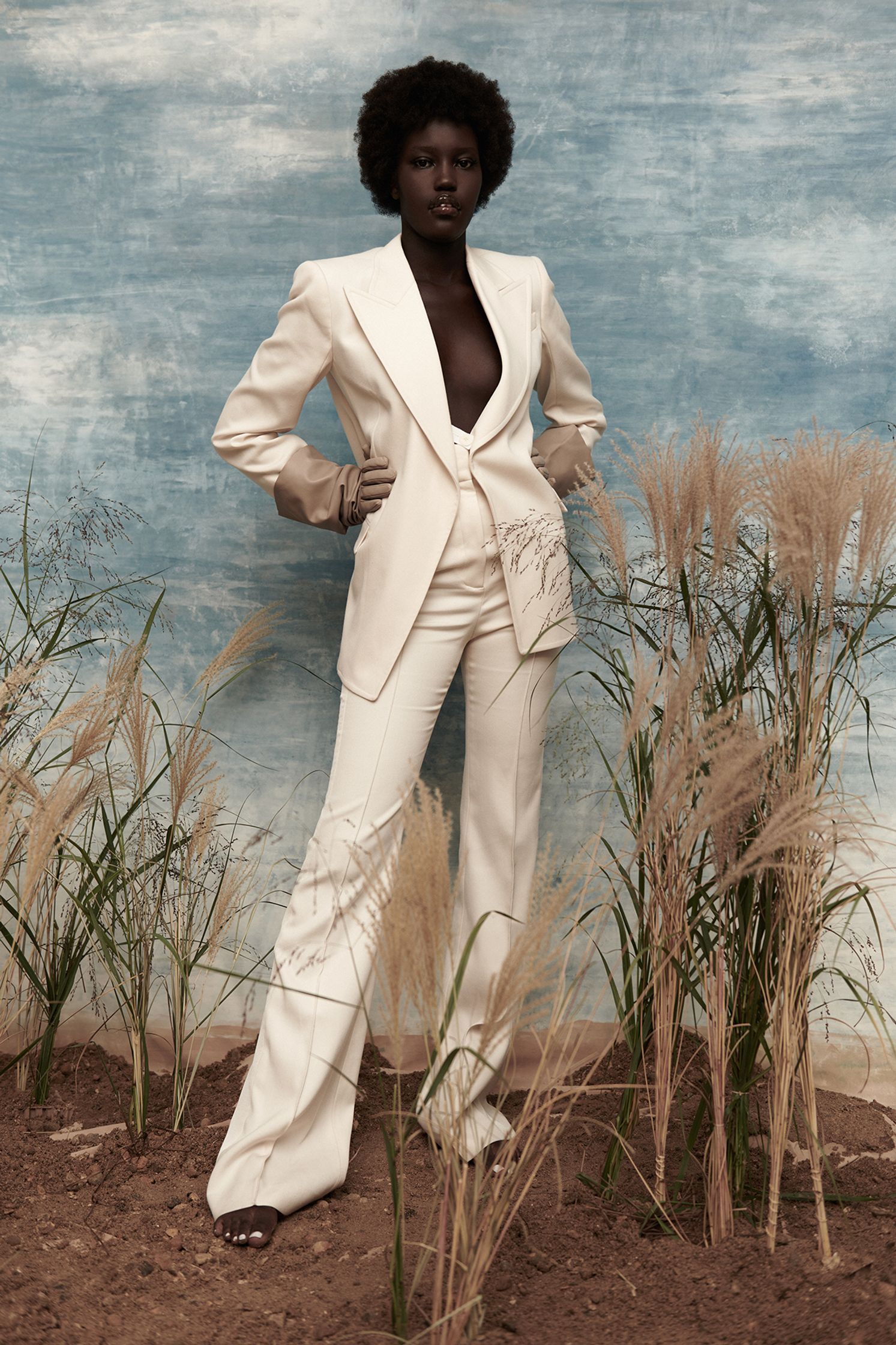 a woman in a white suit standing in a field
