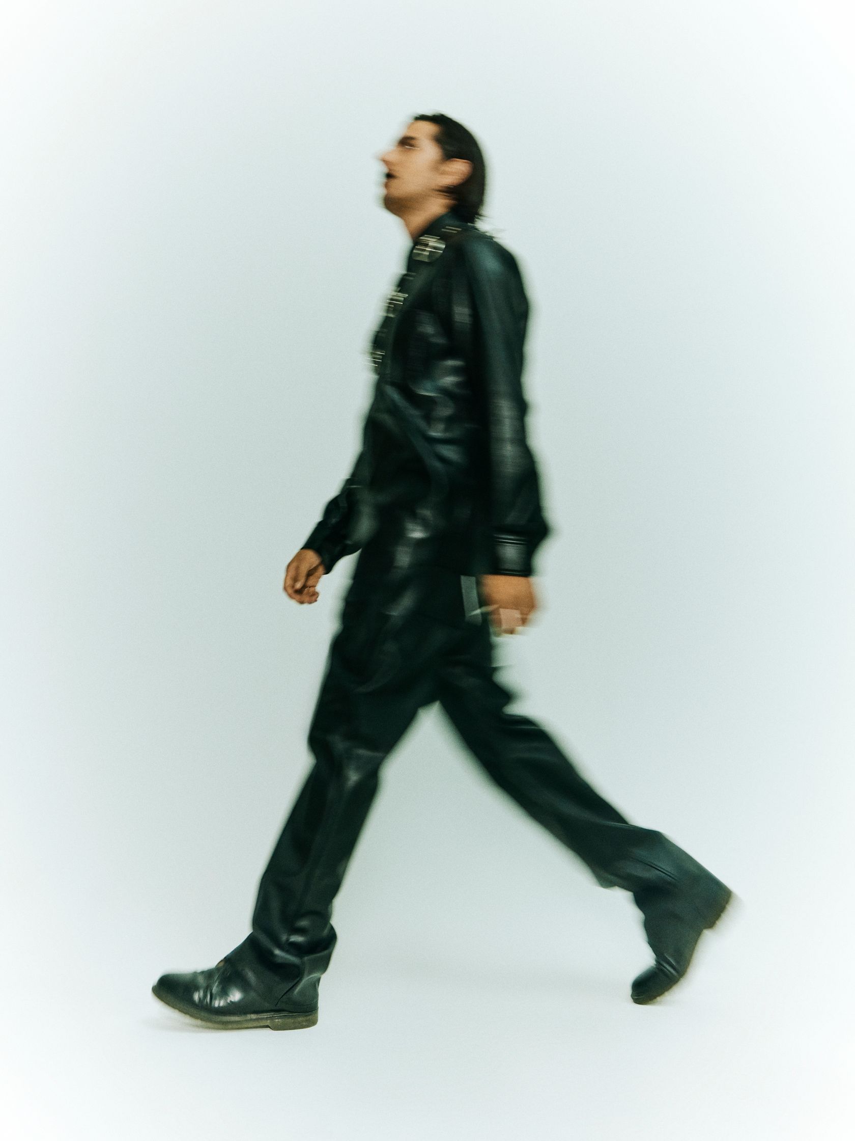 a man in black leather walking on a white background