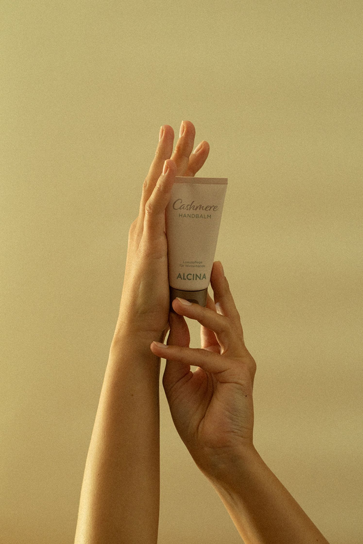 a woman's hand holding a tube of alcina cream