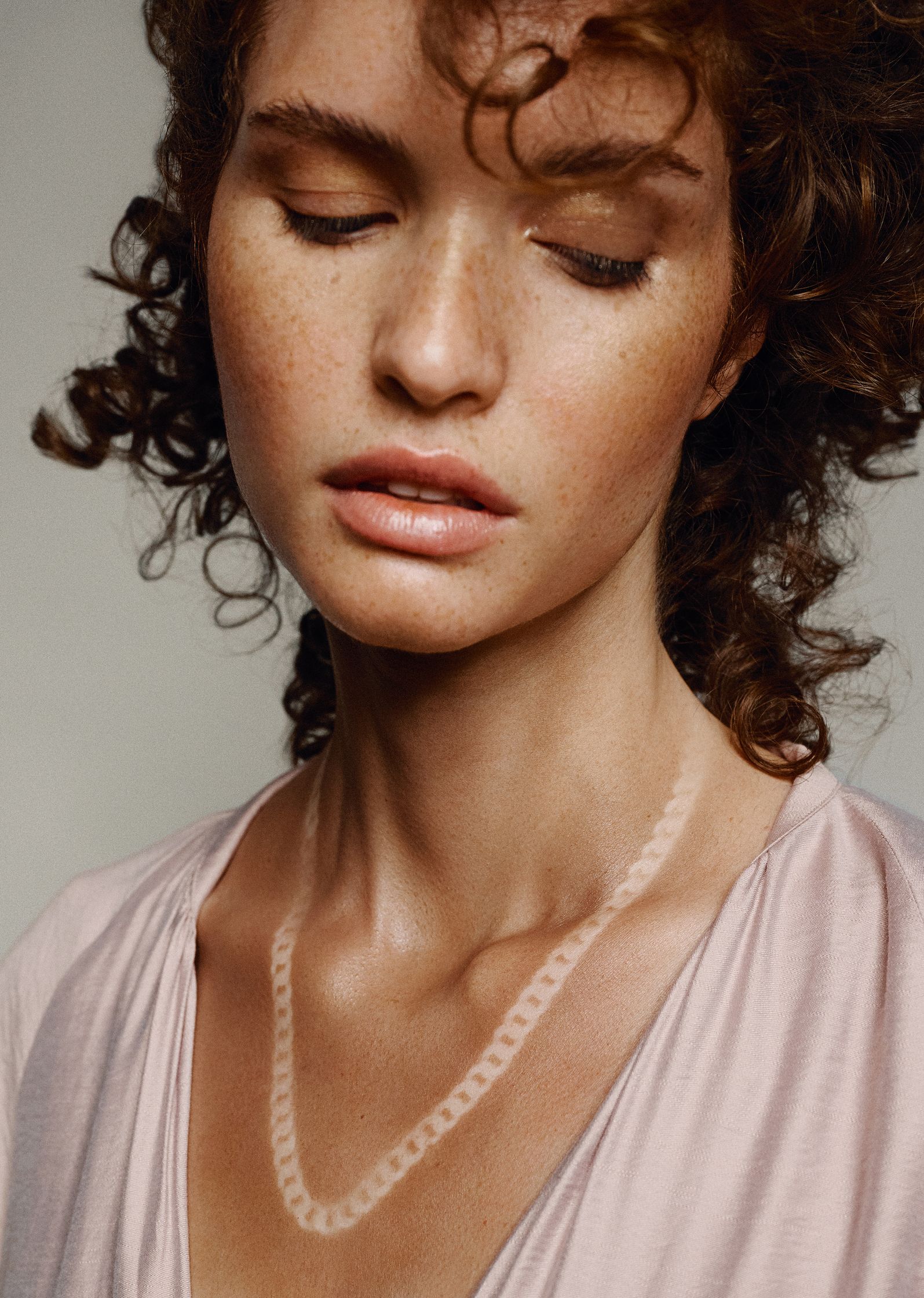 a woman with curly hair wearing a necklace