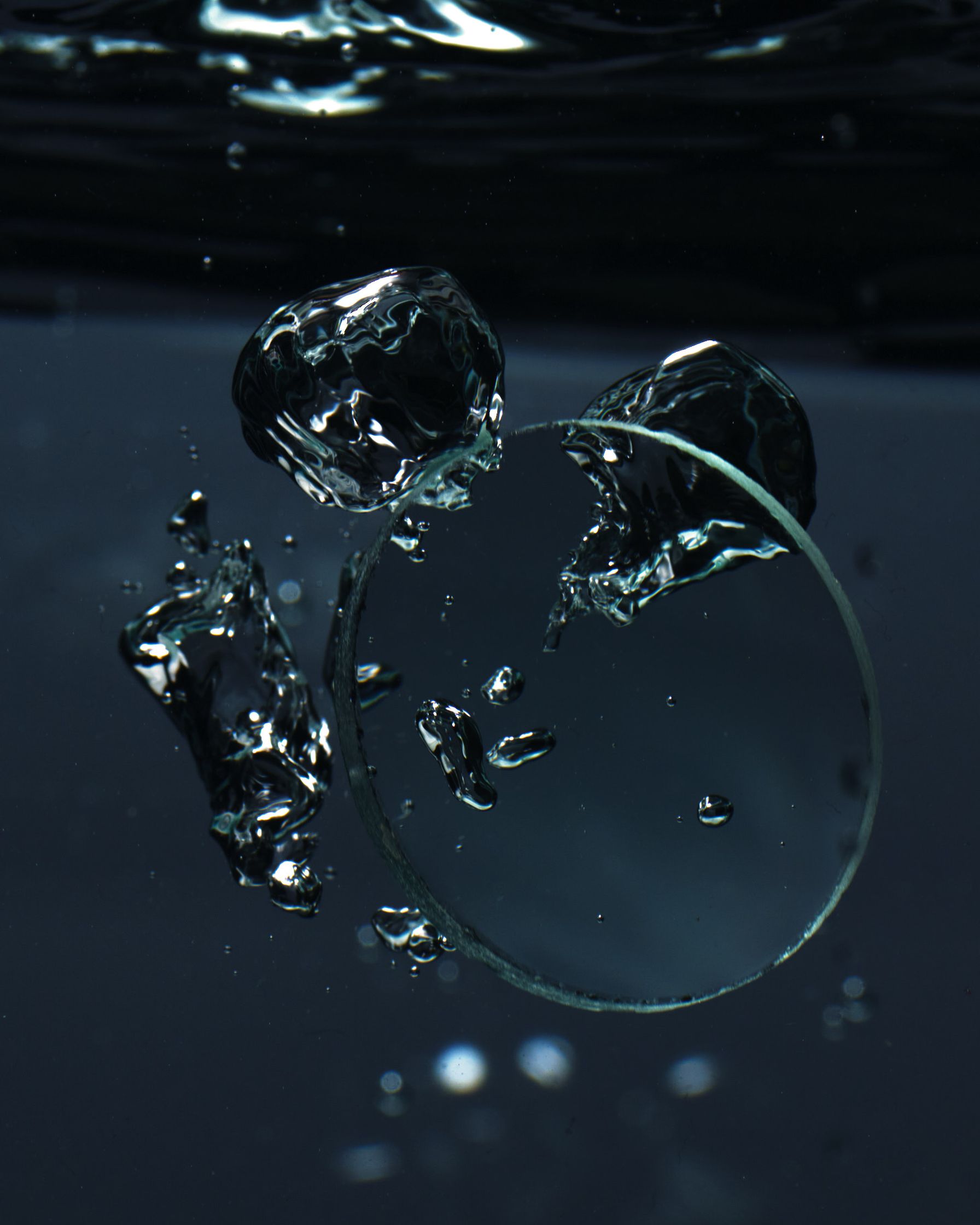 Water splashing around a convex glass disc, showing fluid movement and dynamic reflections.