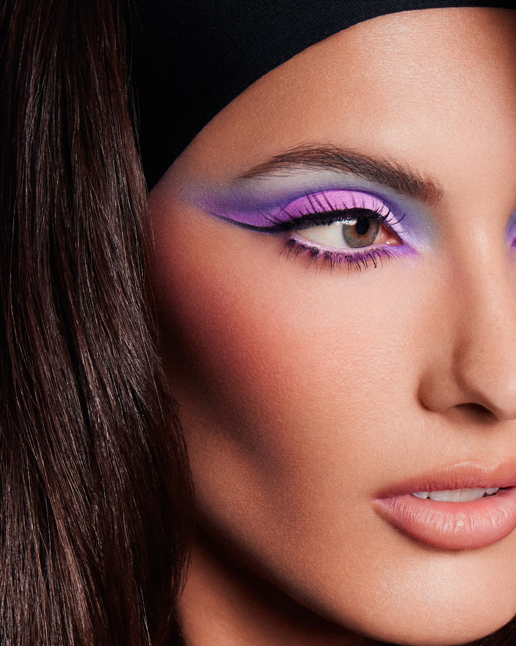 a woman with purple eye makeup and a black hat