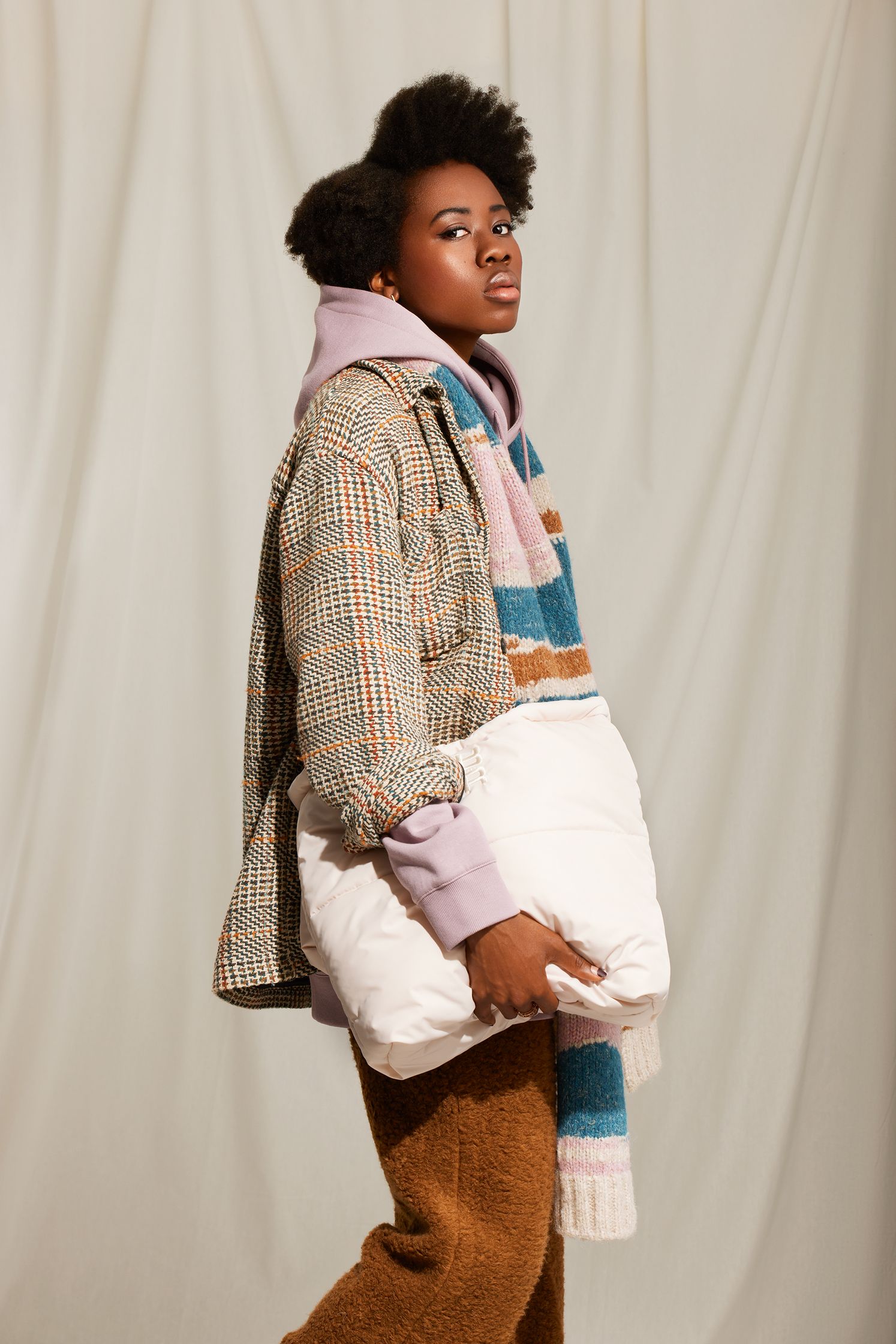 a black woman in a plaid jacket and sweater holding a bag