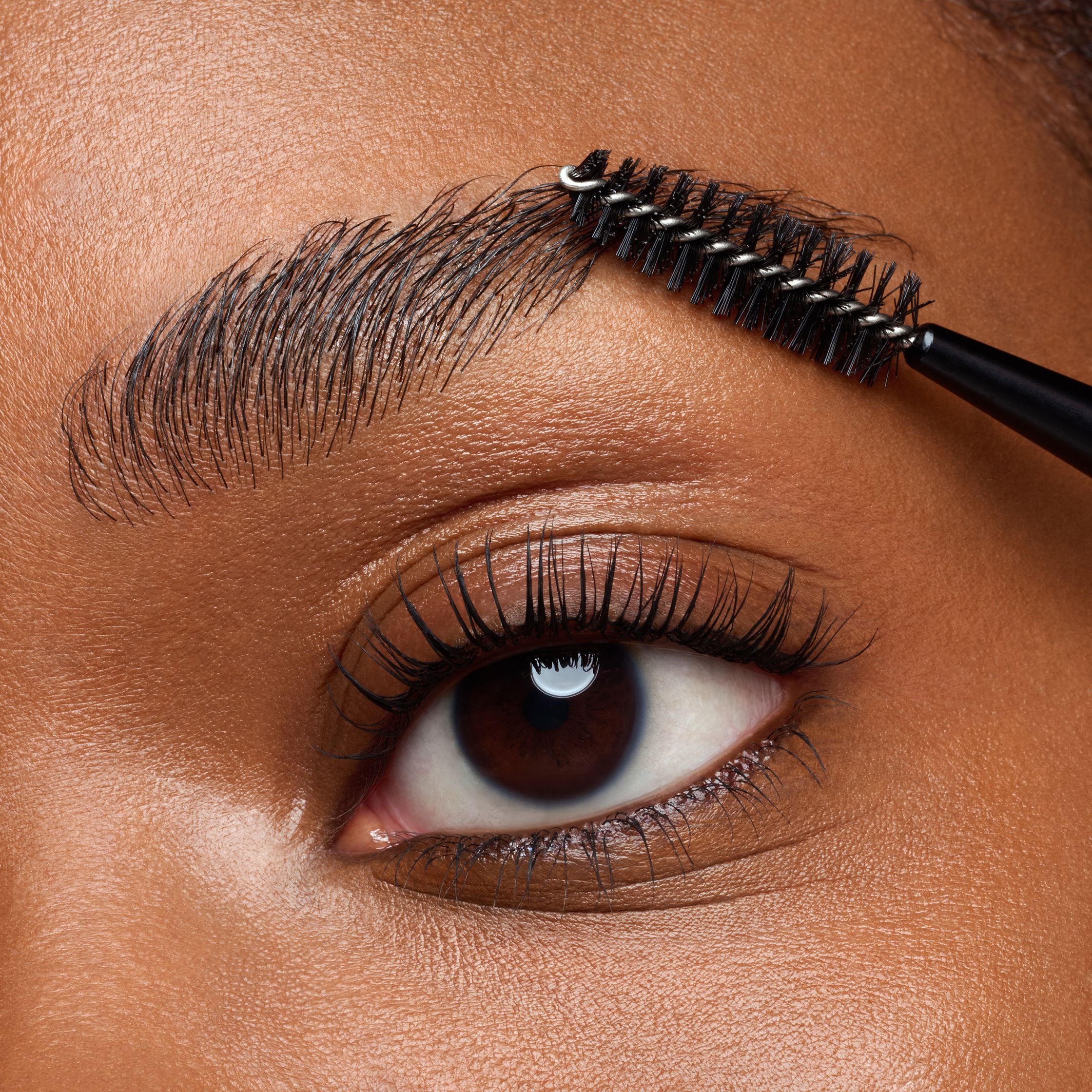 a woman is applying mascara to her eyebrows