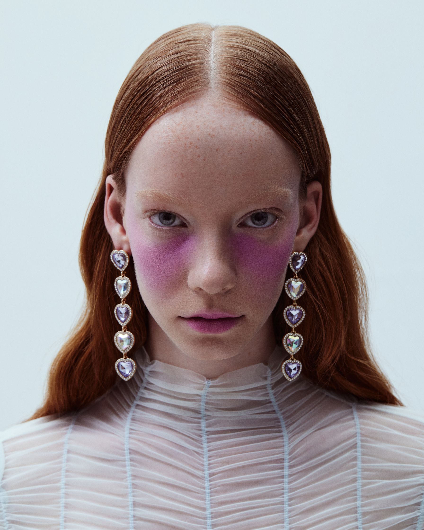 a woman wearing a white dress and pink earrings