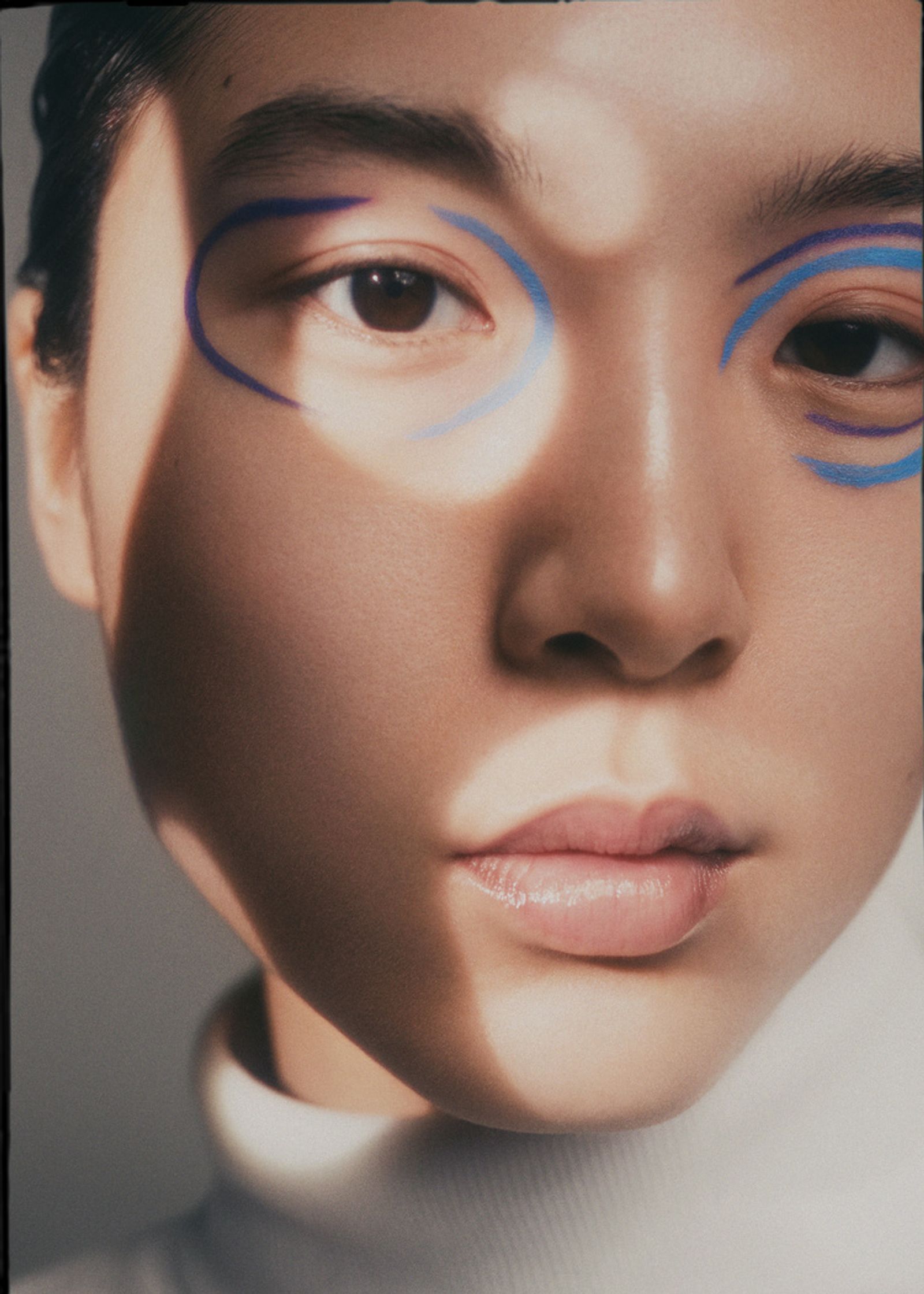 a woman with blue eyeliner is posing for a magazine