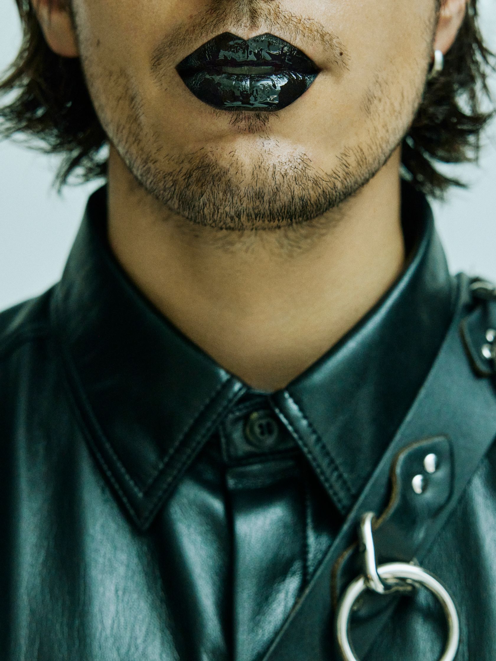 a man wearing a black leather jacket with a chain around his neck