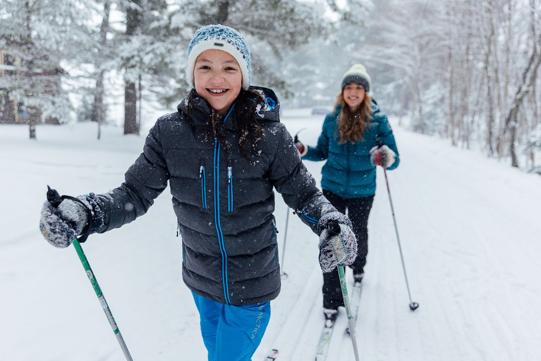 two women skiing down a snowy trail