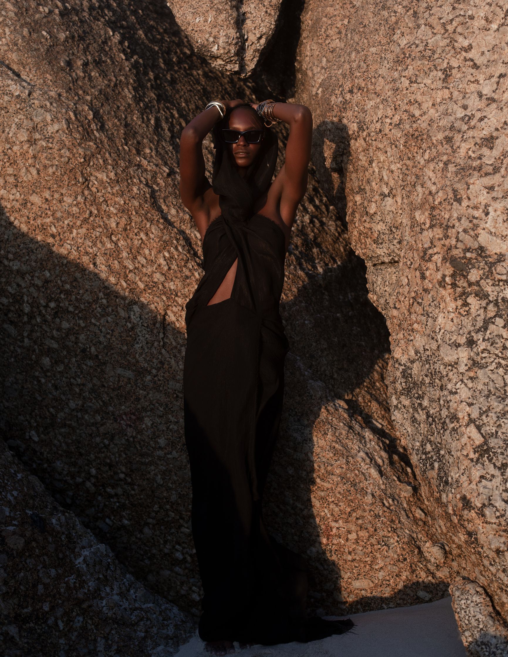 a woman in a black dress posing in front of rocks