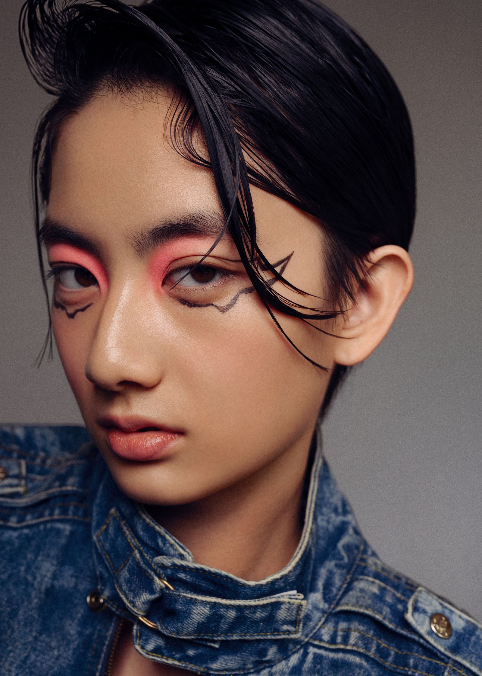 a woman in a denim jacket with pink eye makeup