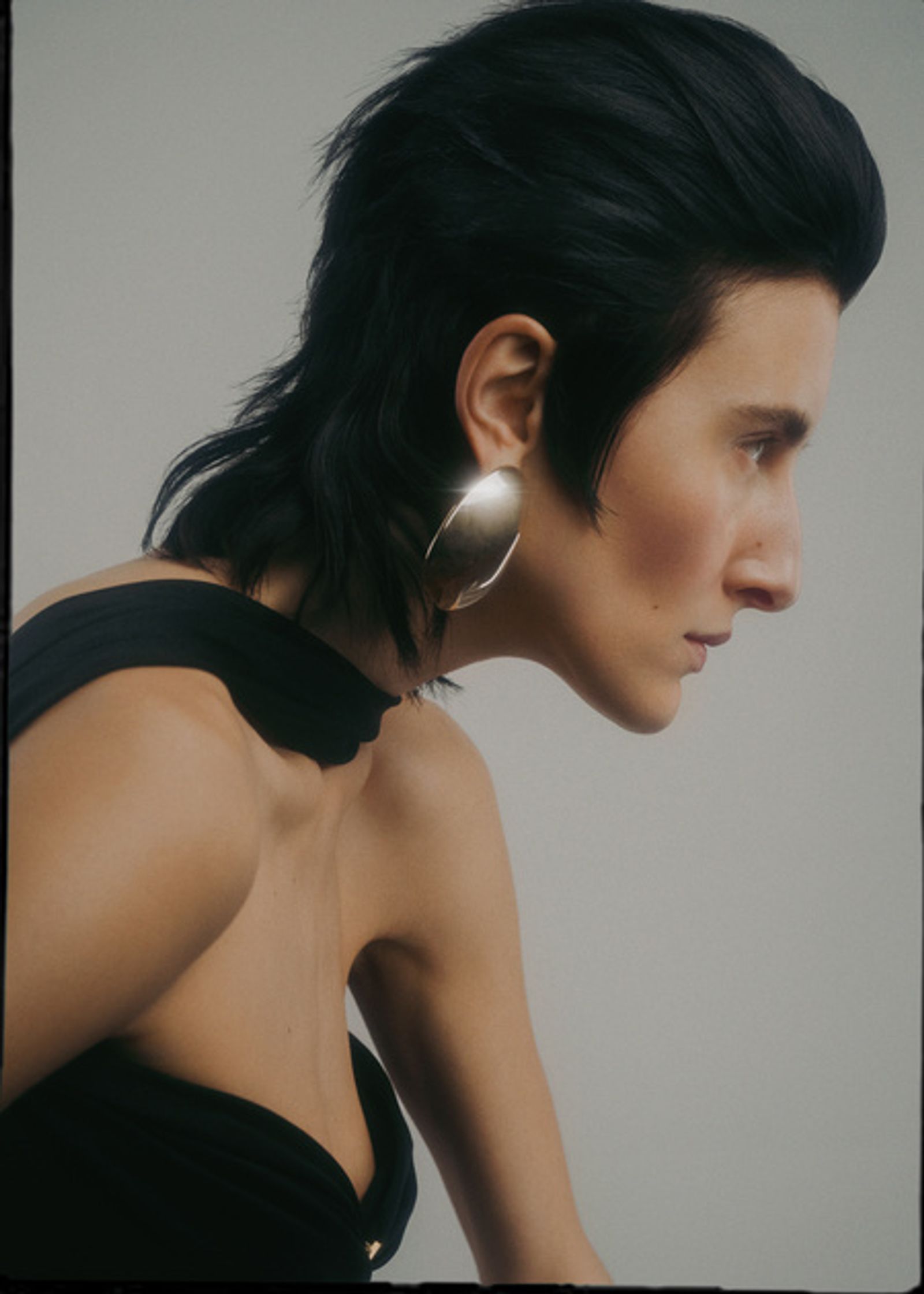 a woman in a black dress with large earrings