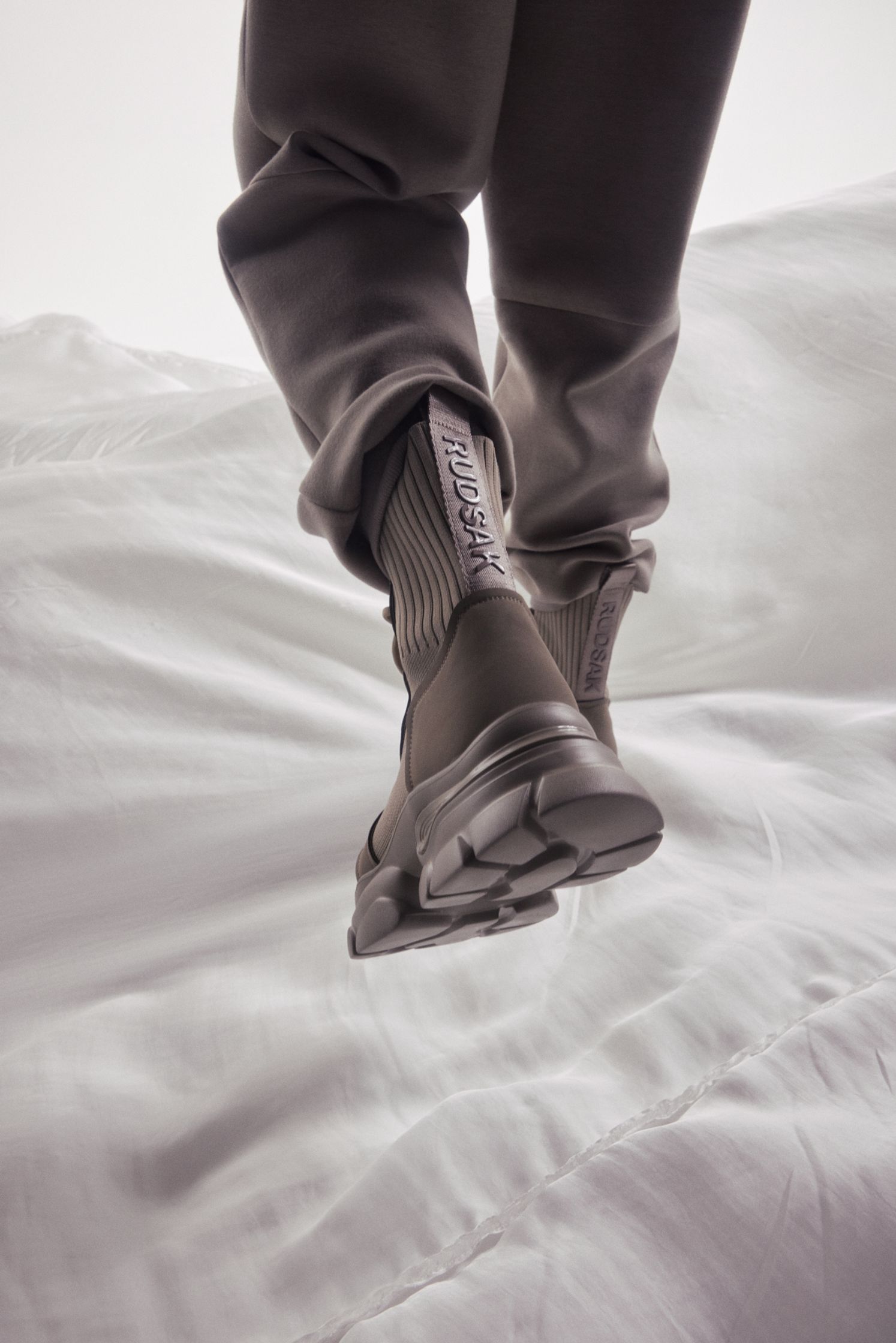 a person standing on top of a white bed wearing sneakers