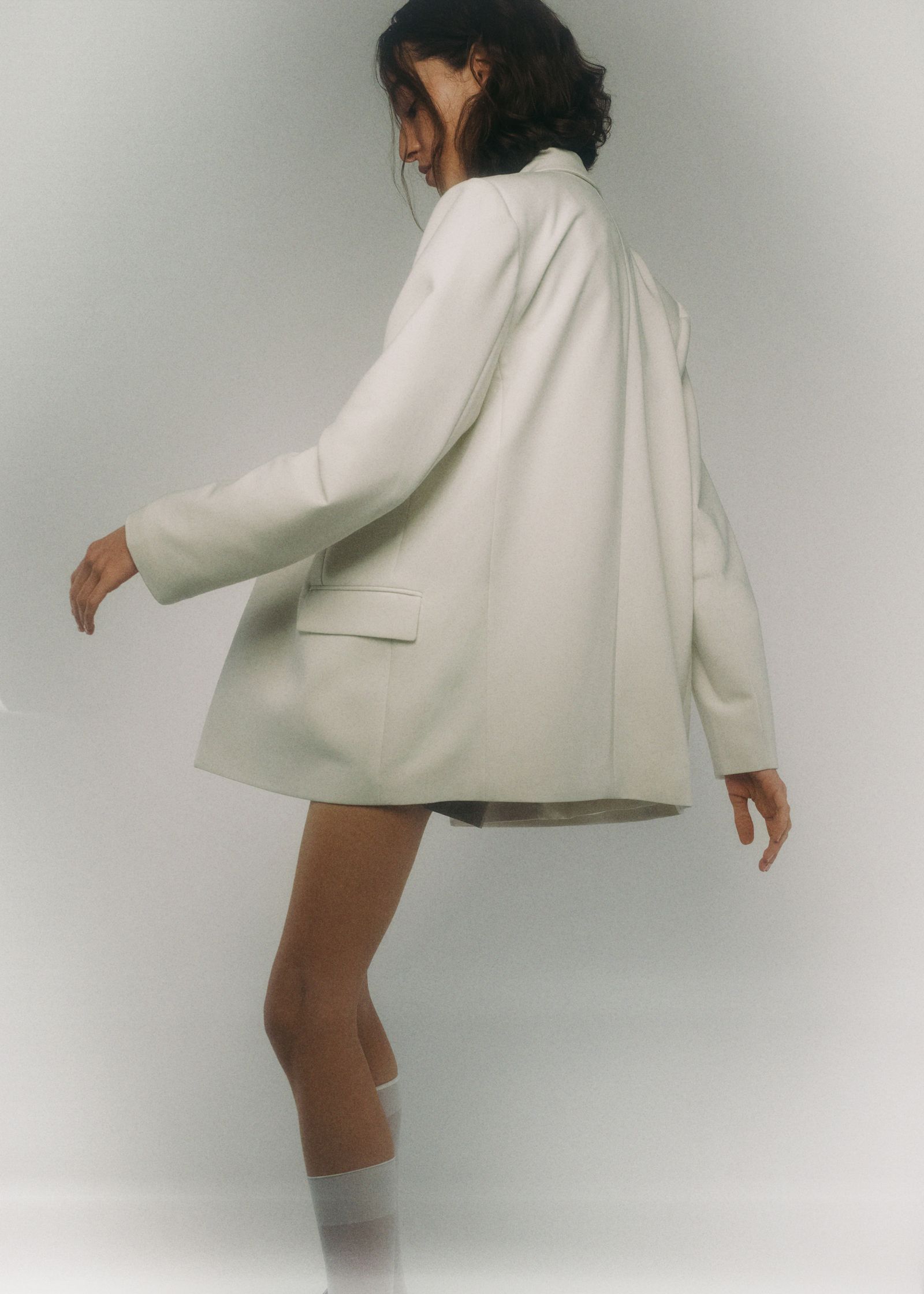 a woman in a white blazer and socks