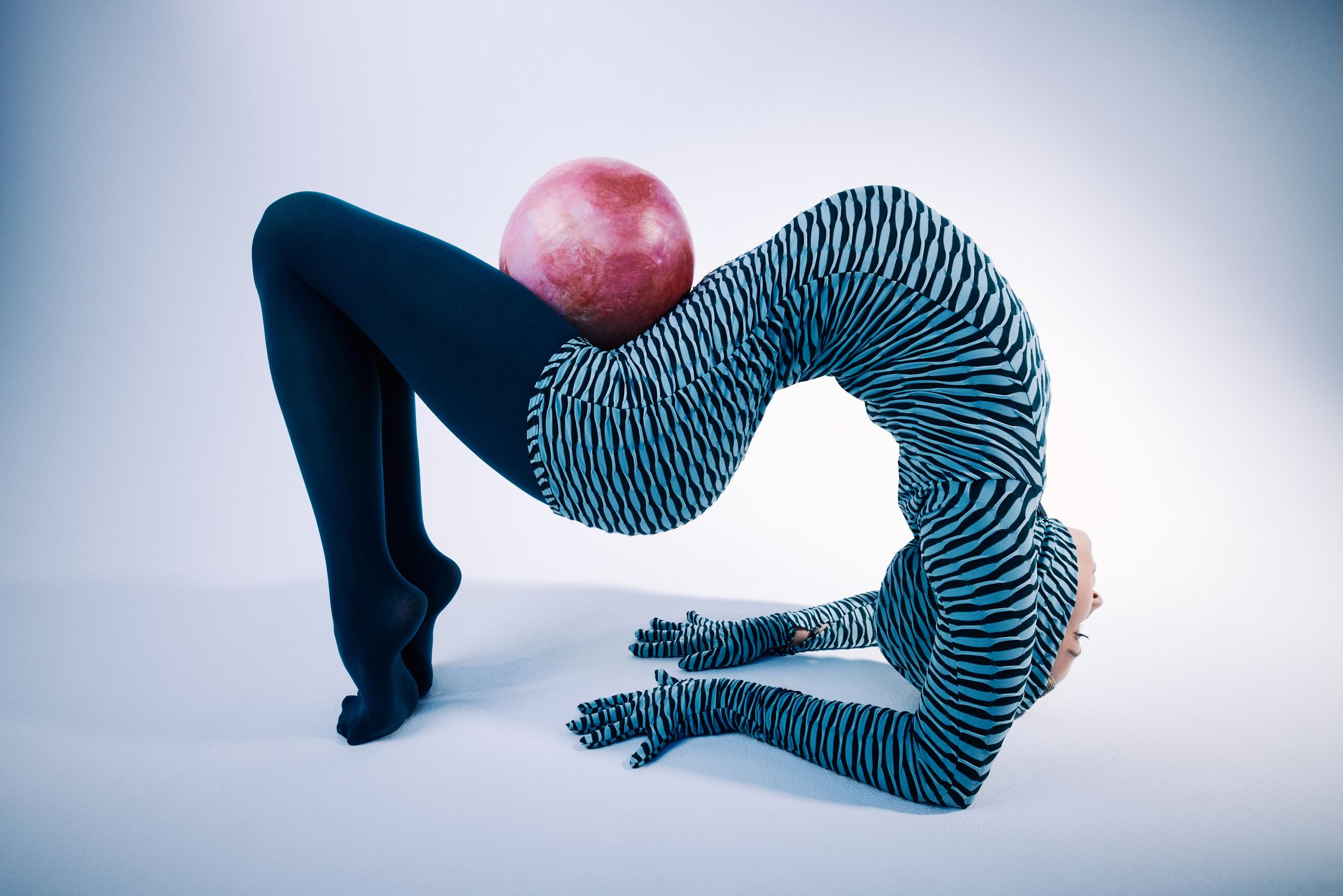 a woman in a zebra print outfit doing a handstand with an apple