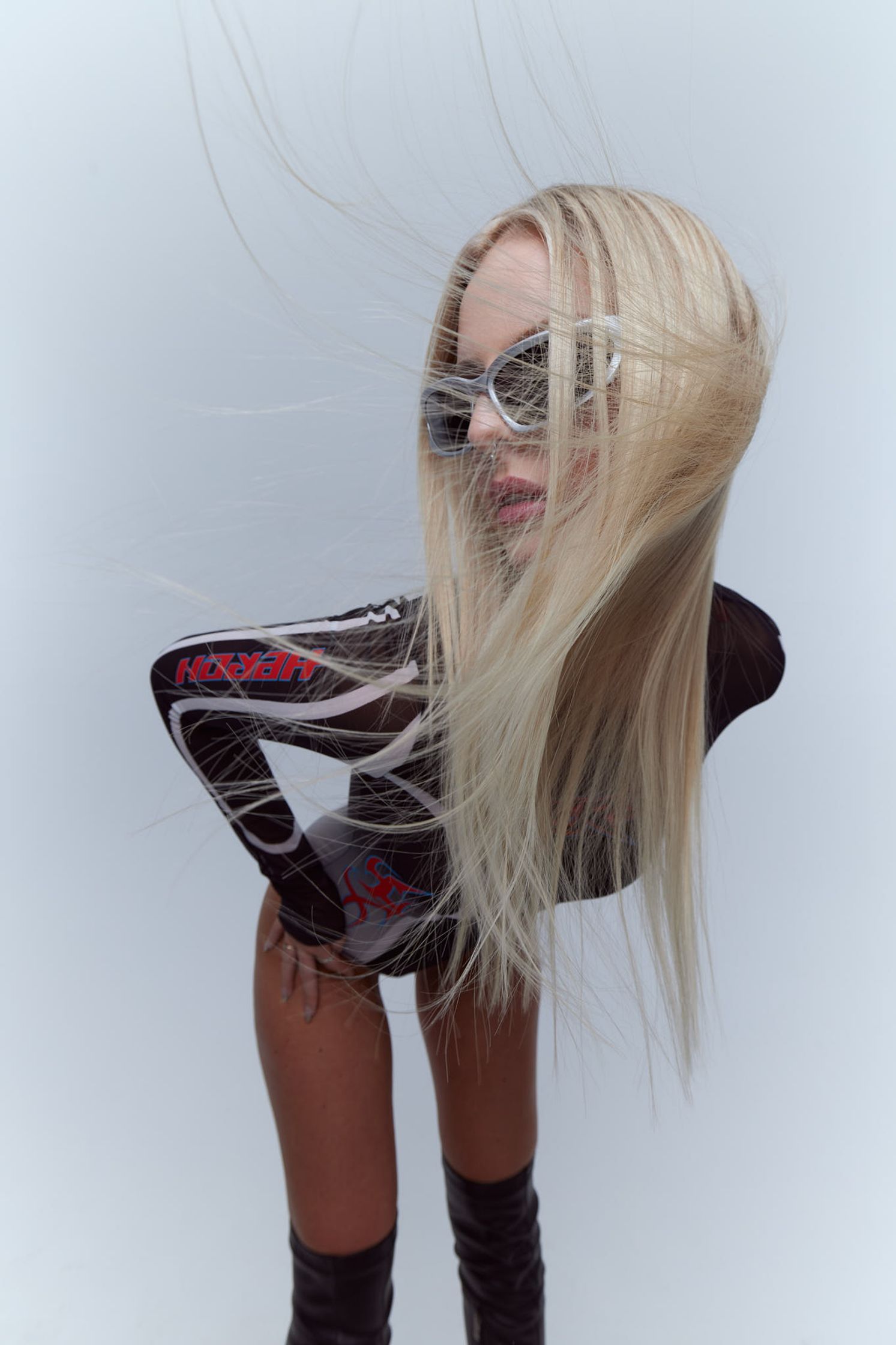 a blond woman in thigh high boots with her hair blowing in the wind