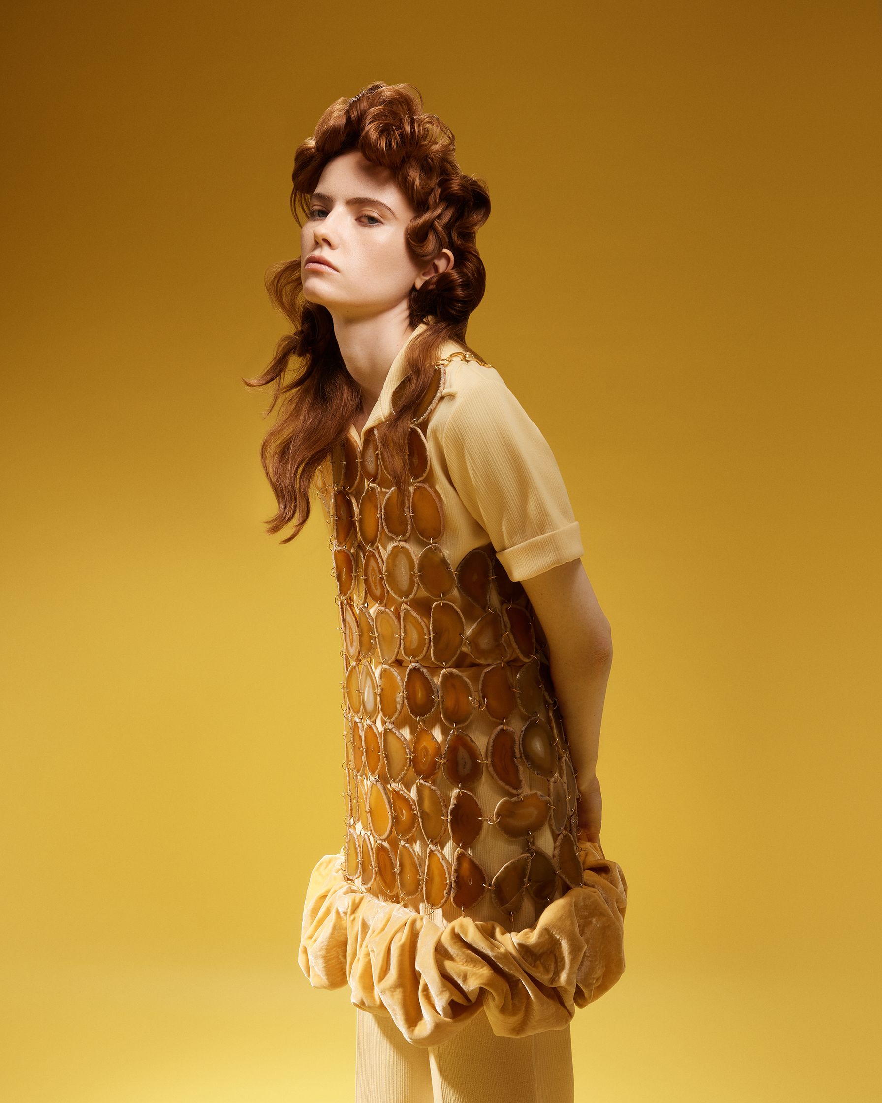 a woman in a yellow dress posing in front of a yellow background