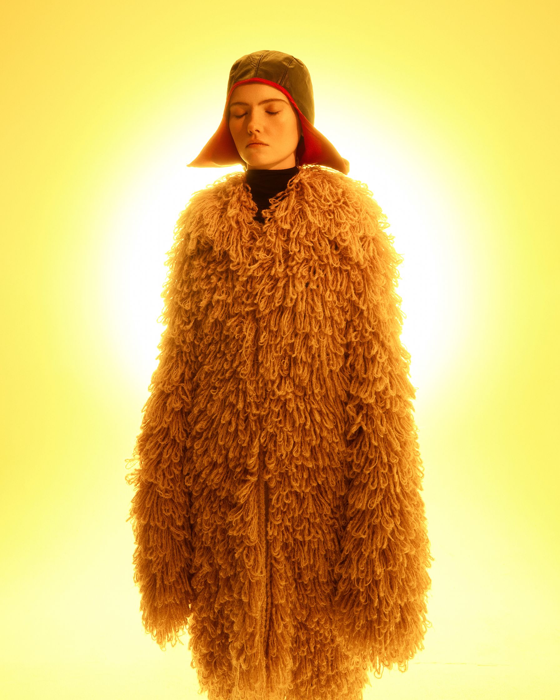 a woman in a fur coat standing in front of a yellow light