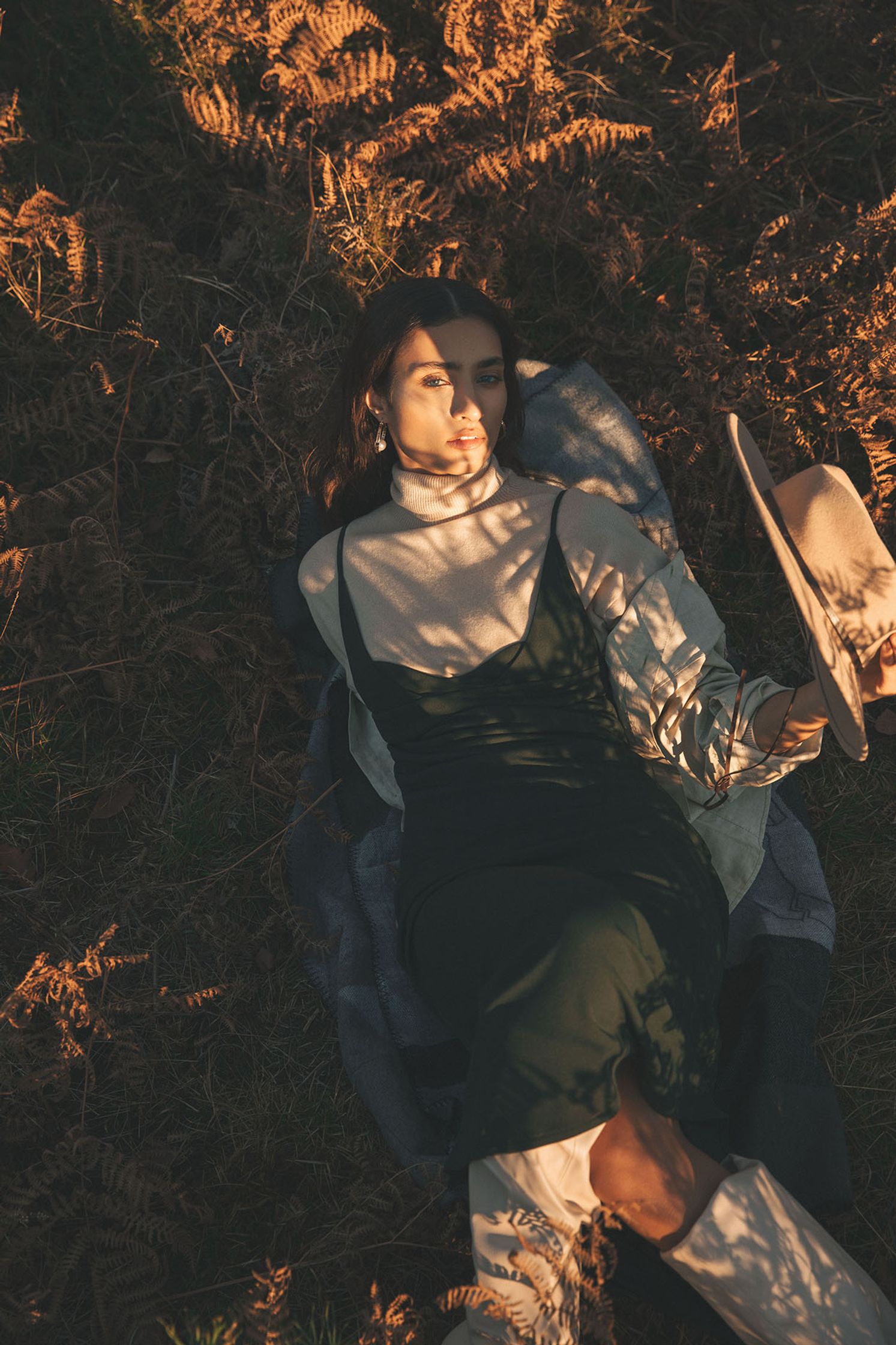 a woman laying in the grass with a hat on her head