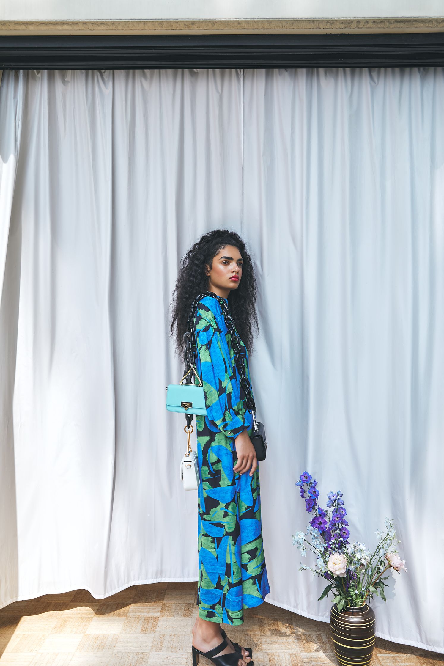 a woman in a blue camouflage print dress standing in front of a curtain