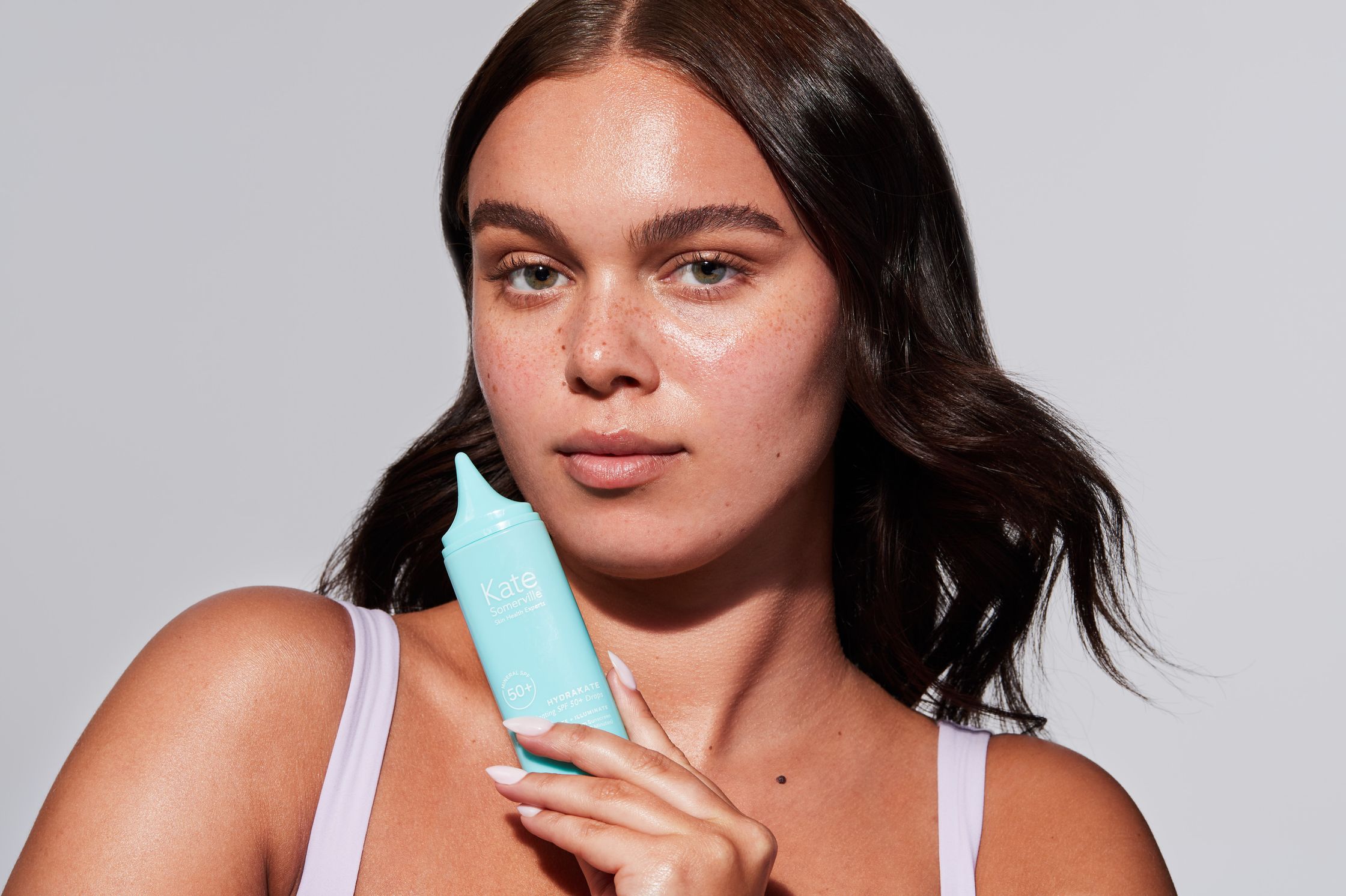 a woman holding a tube of sunscreen