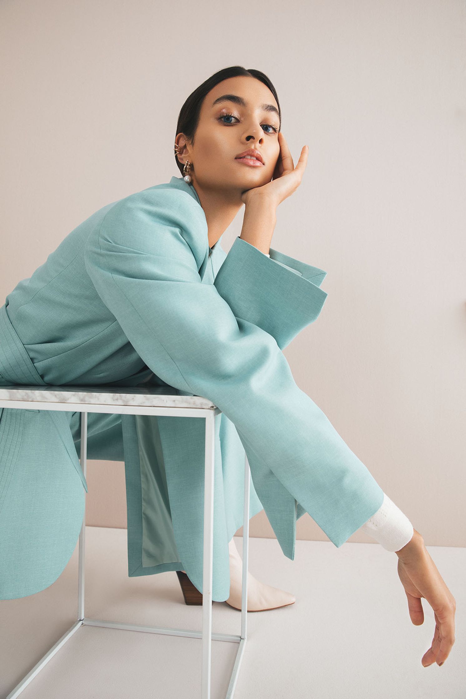a woman in a blue coat posing on a chair