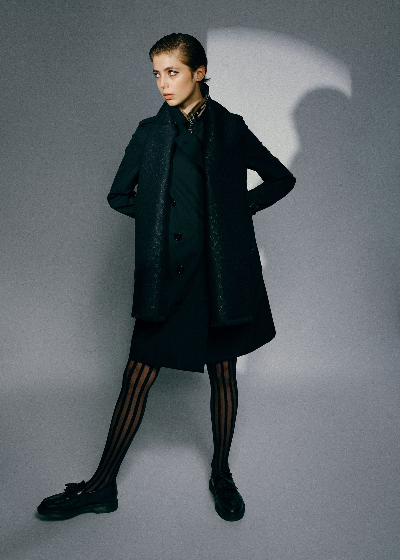 a woman in a black coat and stockings posing for a photo