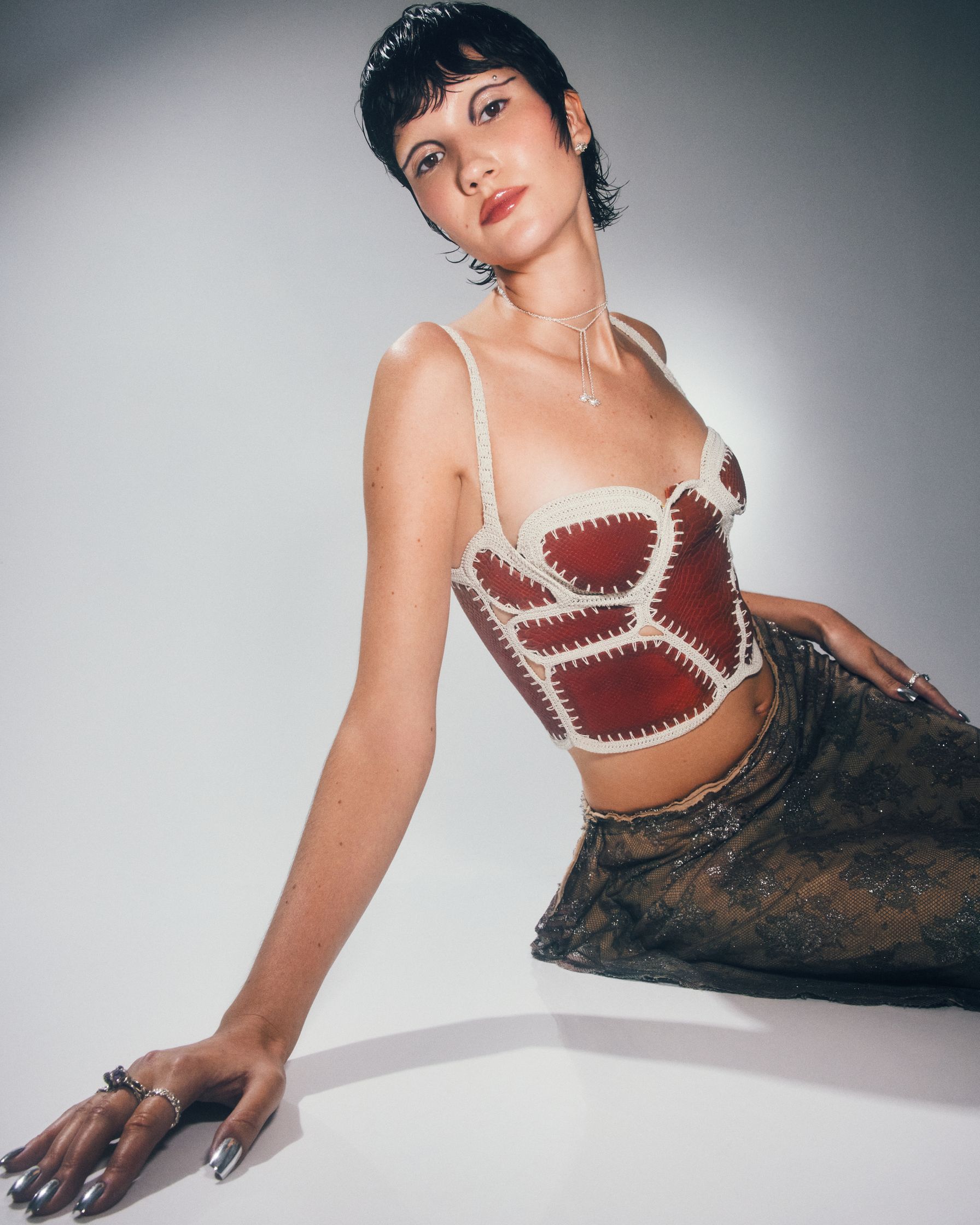 a woman in a red and brown top posing on the floor