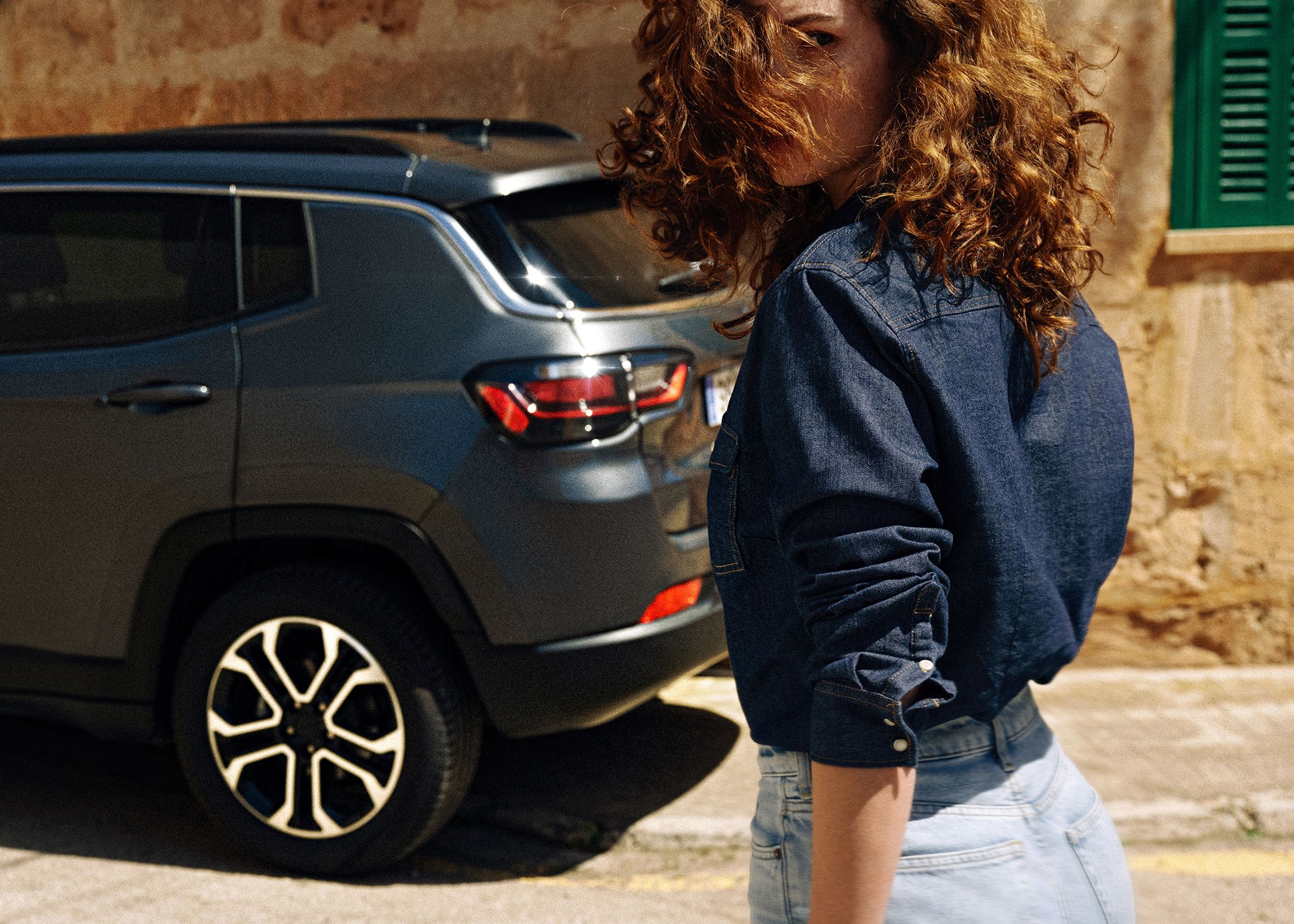 a woman is standing next to a jeep compass