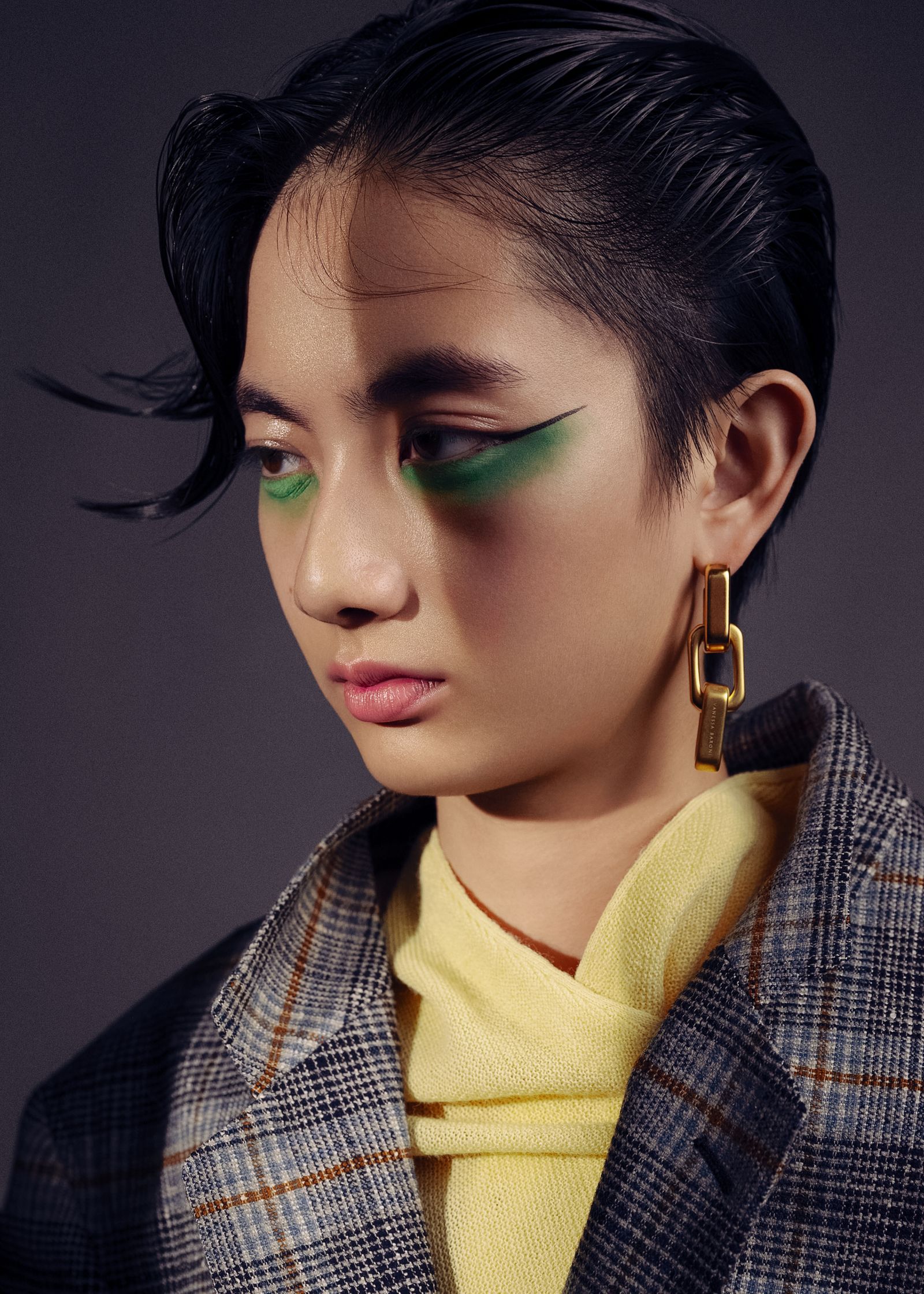 a young woman with green eye makeup and a plaid jacket