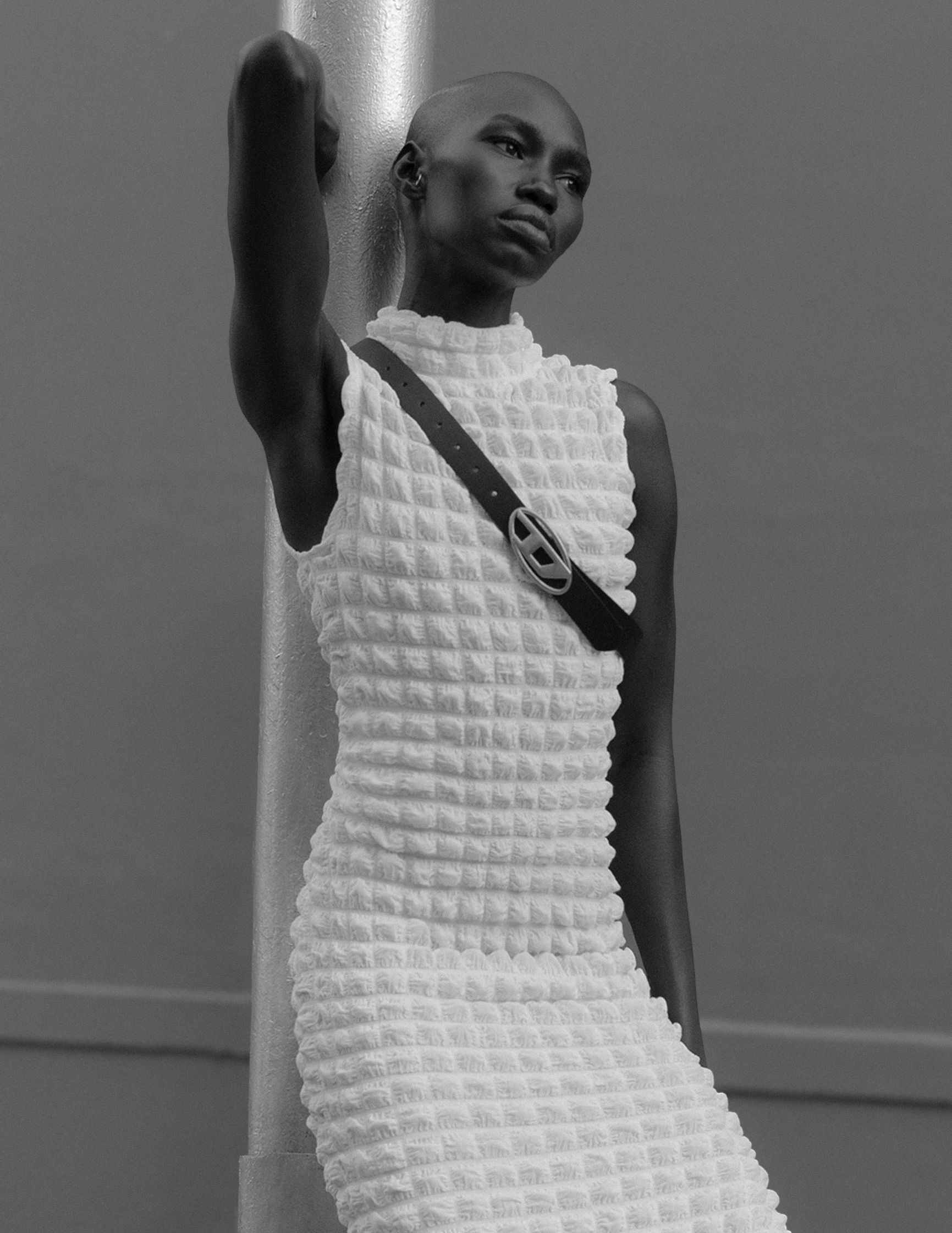 a woman in a white dress leaning against a pole