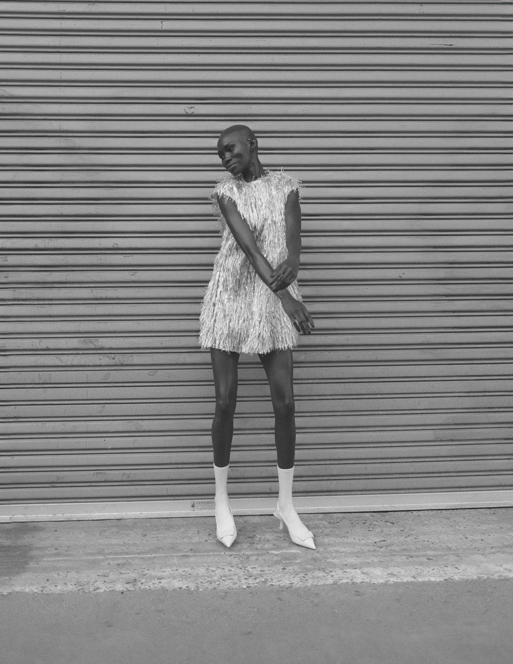 a black and white photo of a woman leaning against a wall