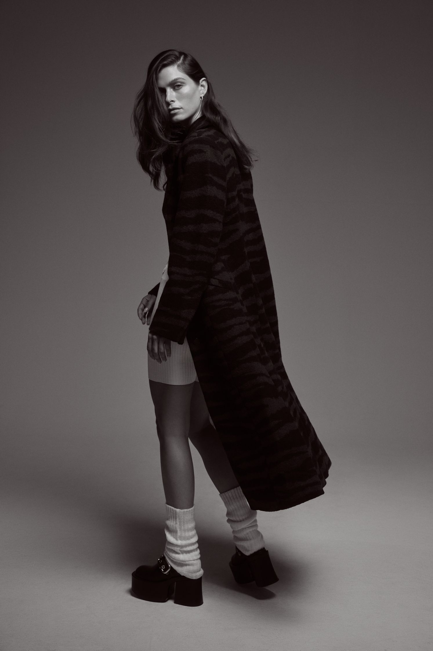 a black and white photo of a woman in a coat and socks