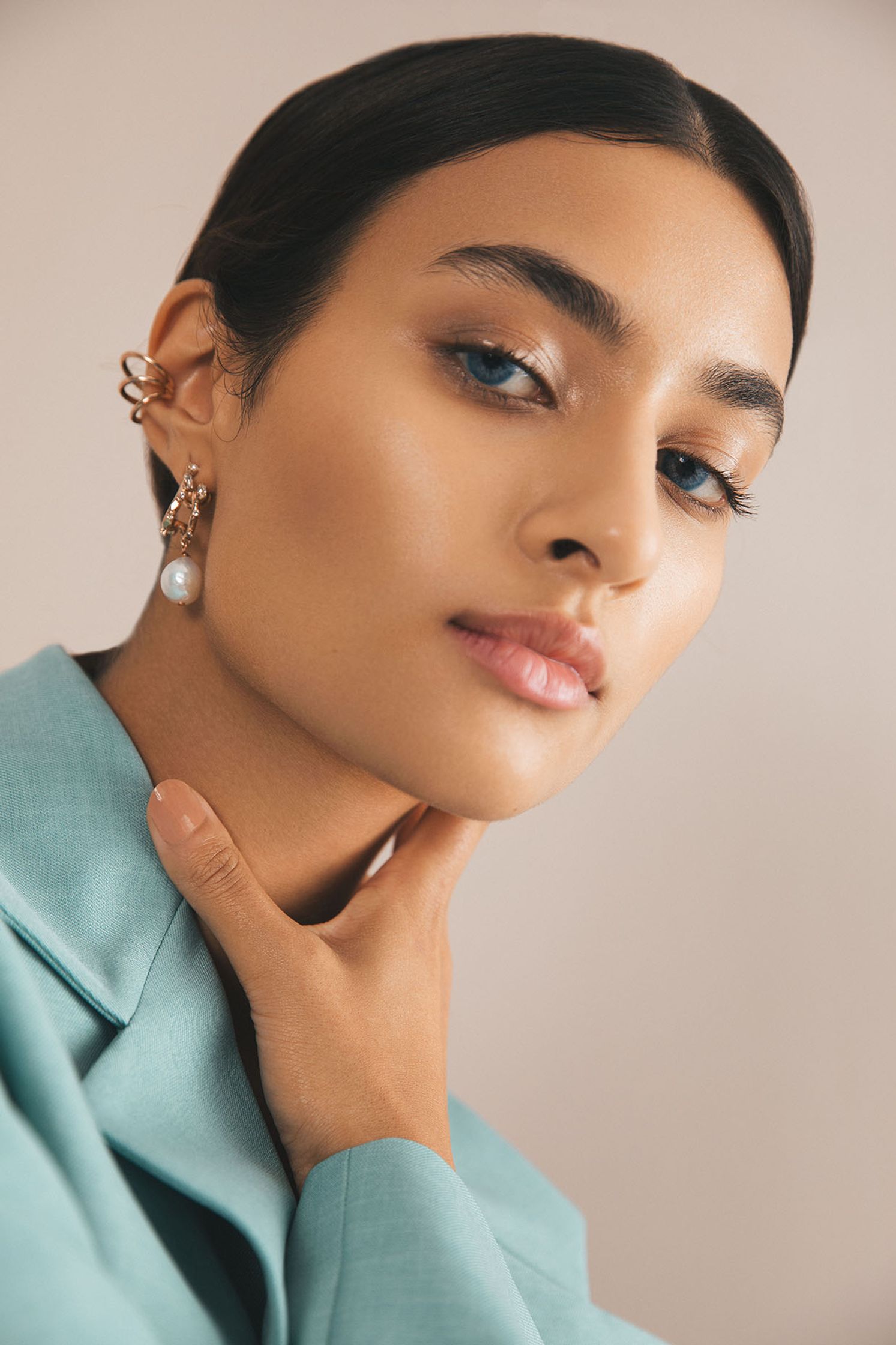 a woman wearing a blue suit and pearl earrings