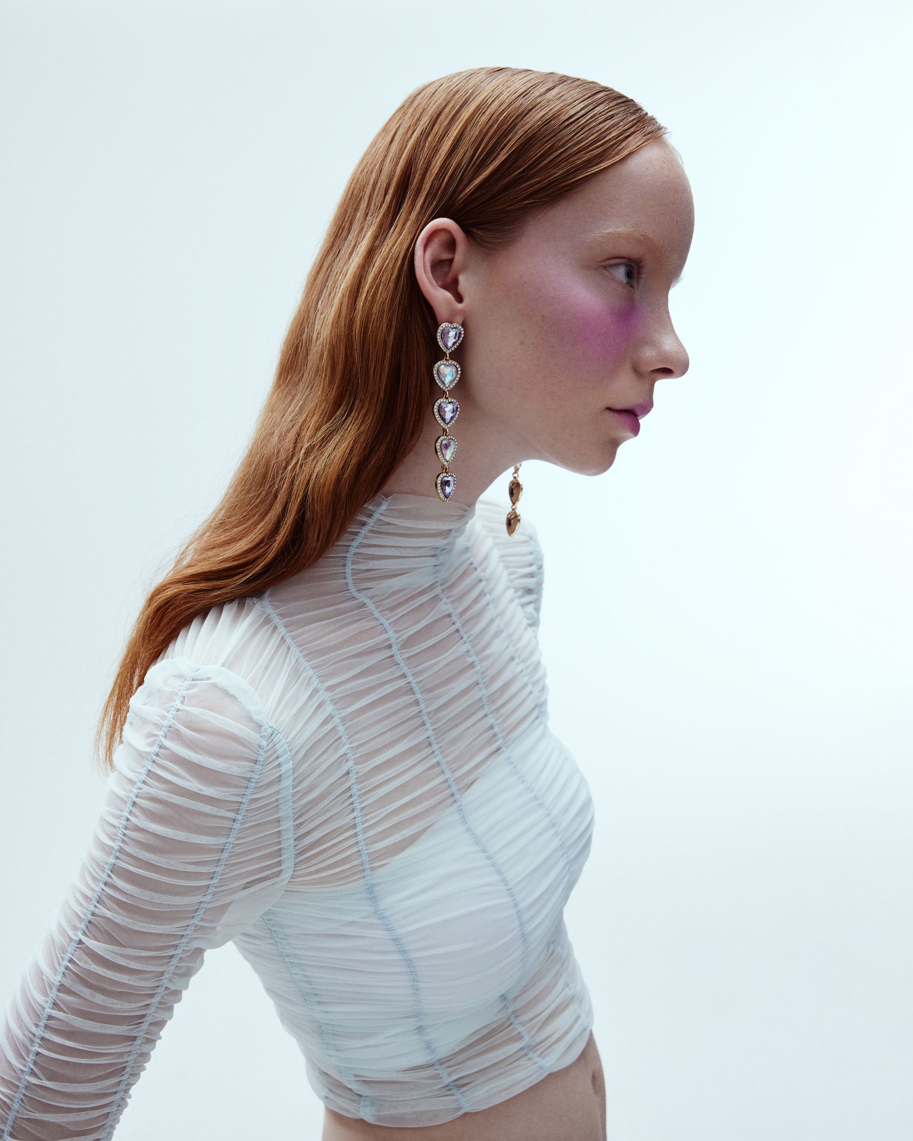 a woman wearing a white top and earrings