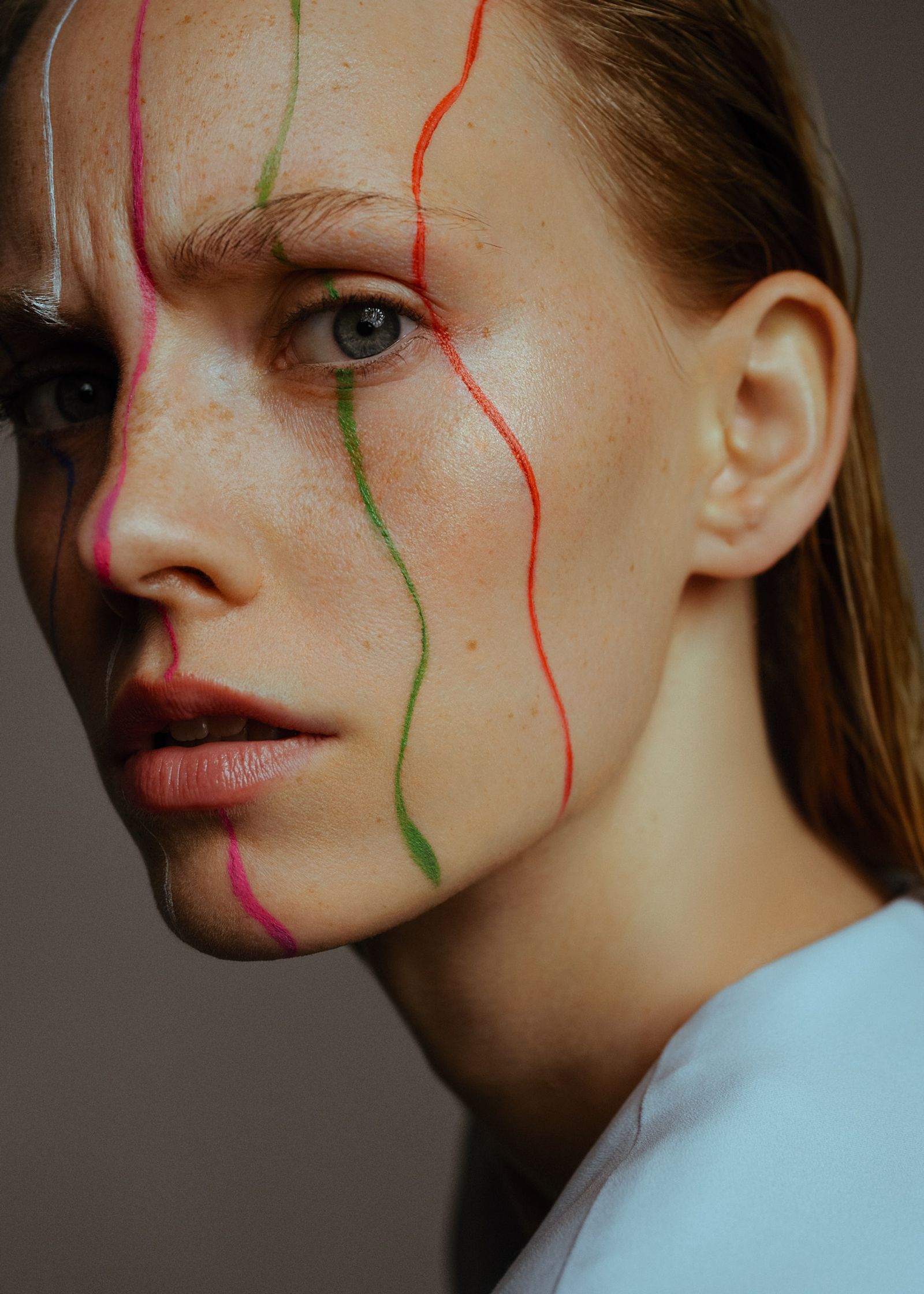 a woman with colorful lines painted on her face