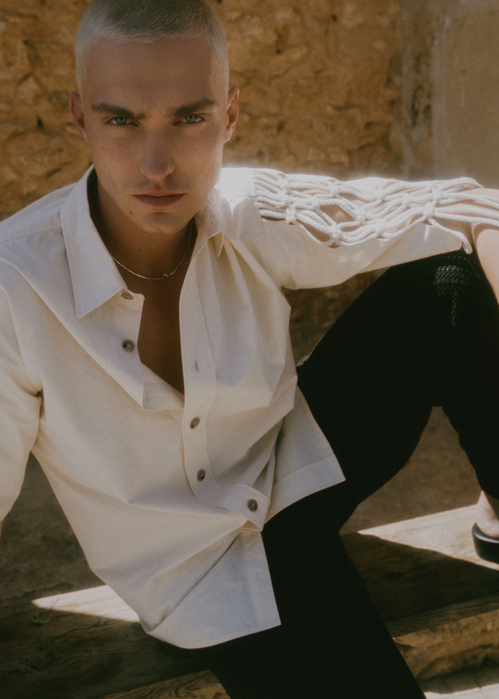 a young man wearing a white shirt and black pants